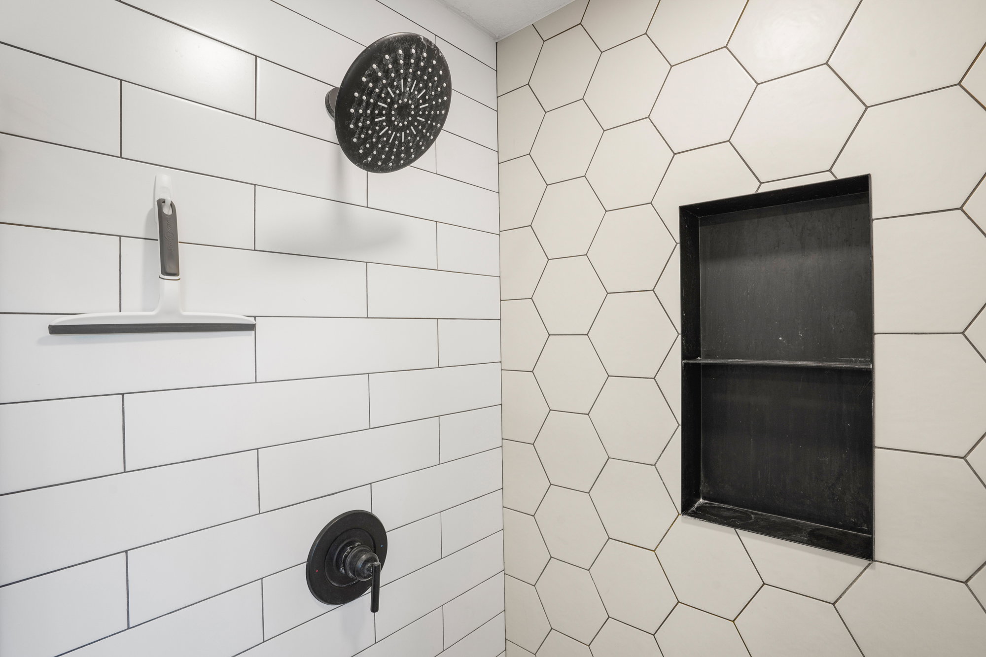 Shower enclosure featuring white subway tile, a dark-finish rainfall showerhead, and a matching dark-finish control valve