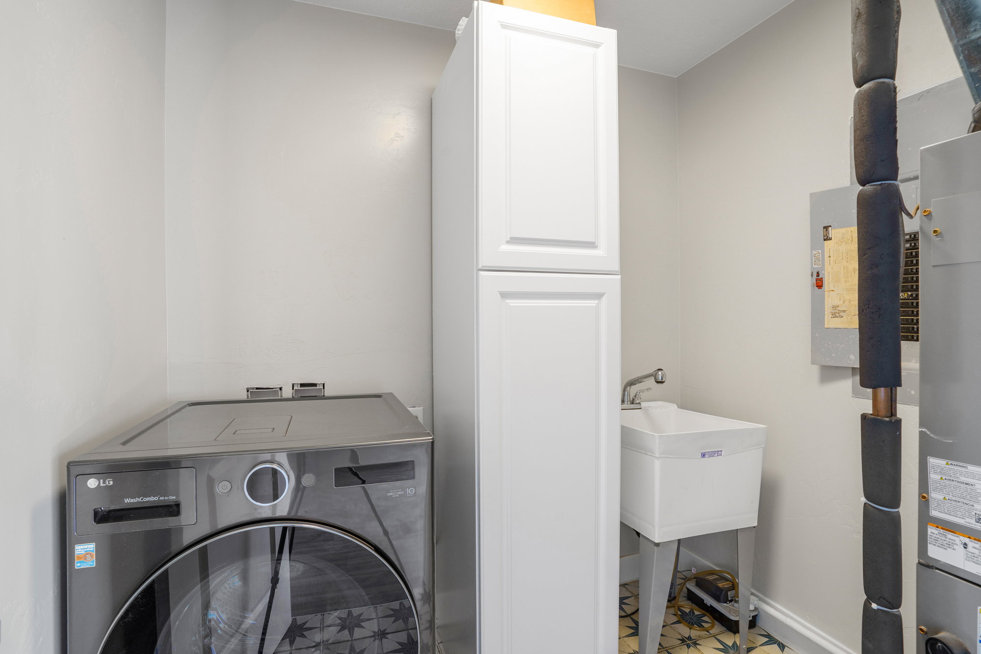 Utility room featuring patterned floor tile, a tall built-in storage cabinet, and a utility sink
