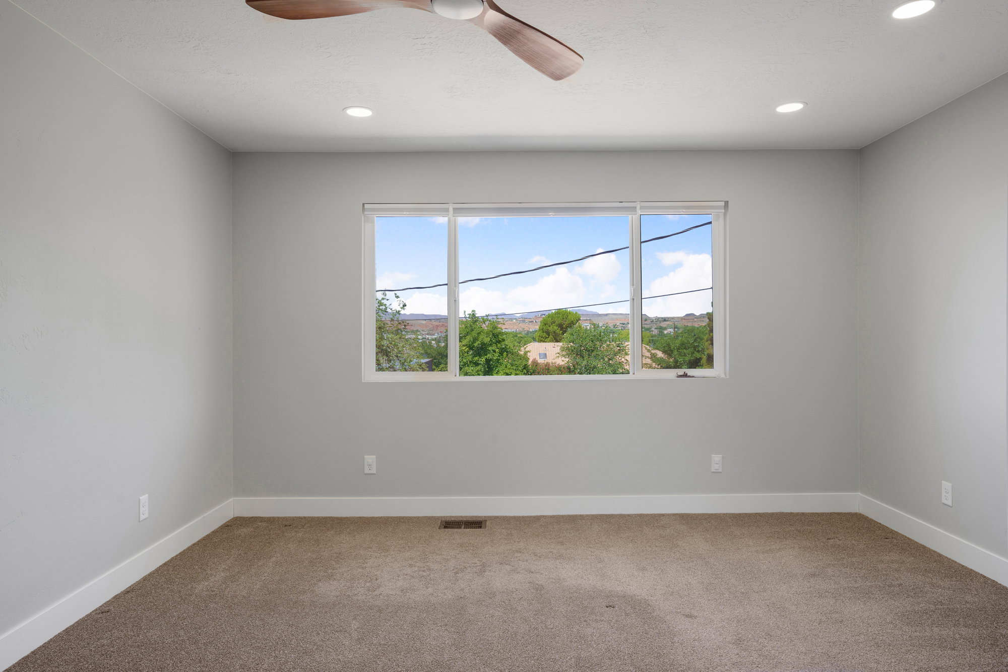 Bright room featuring a large window, recessed lighting, a ceiling fan, light gray walls, and carpeting