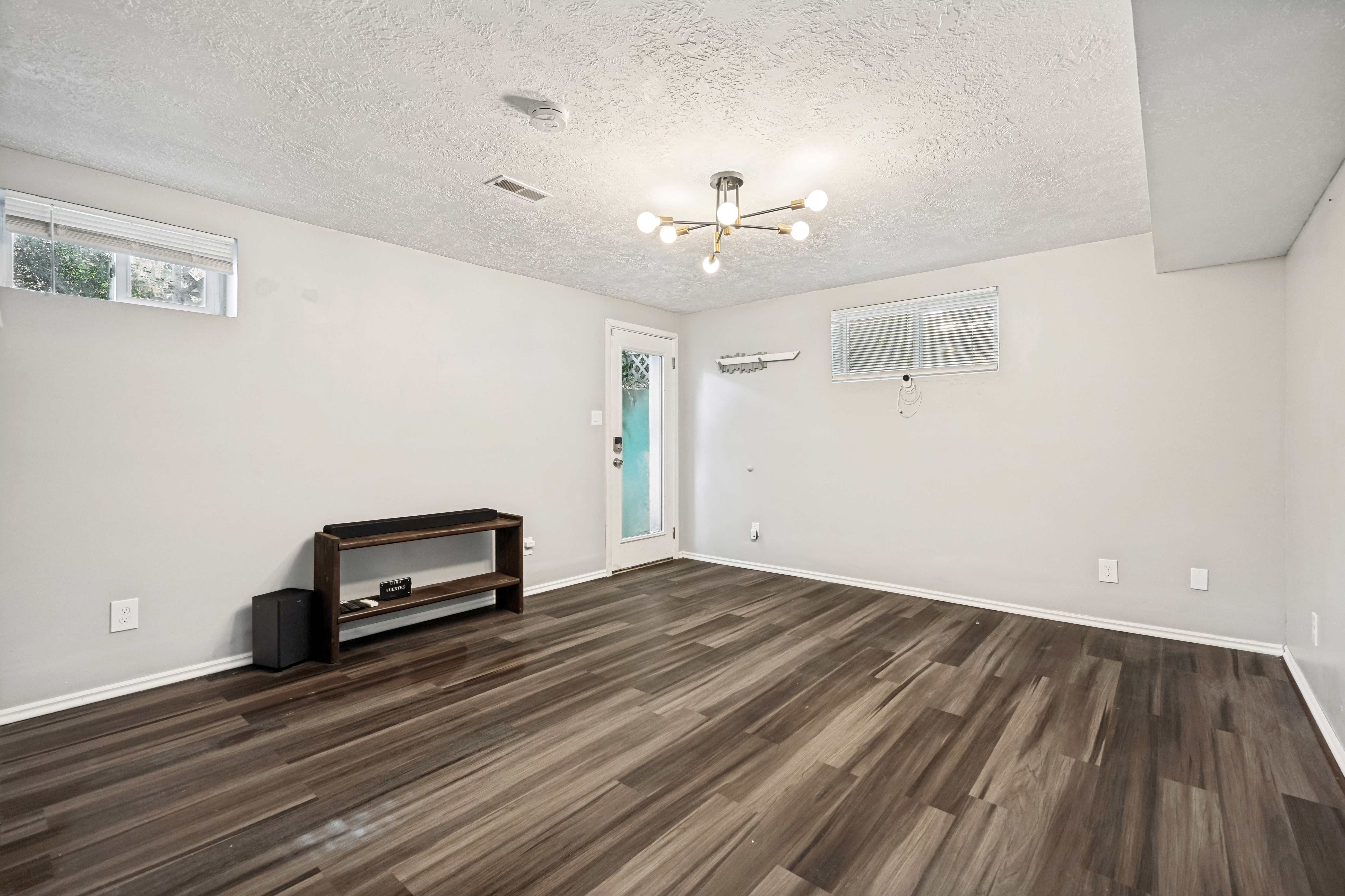 Spacious interior featuring wood-finish flooring, light grey walls, and a contemporary ceiling fixture