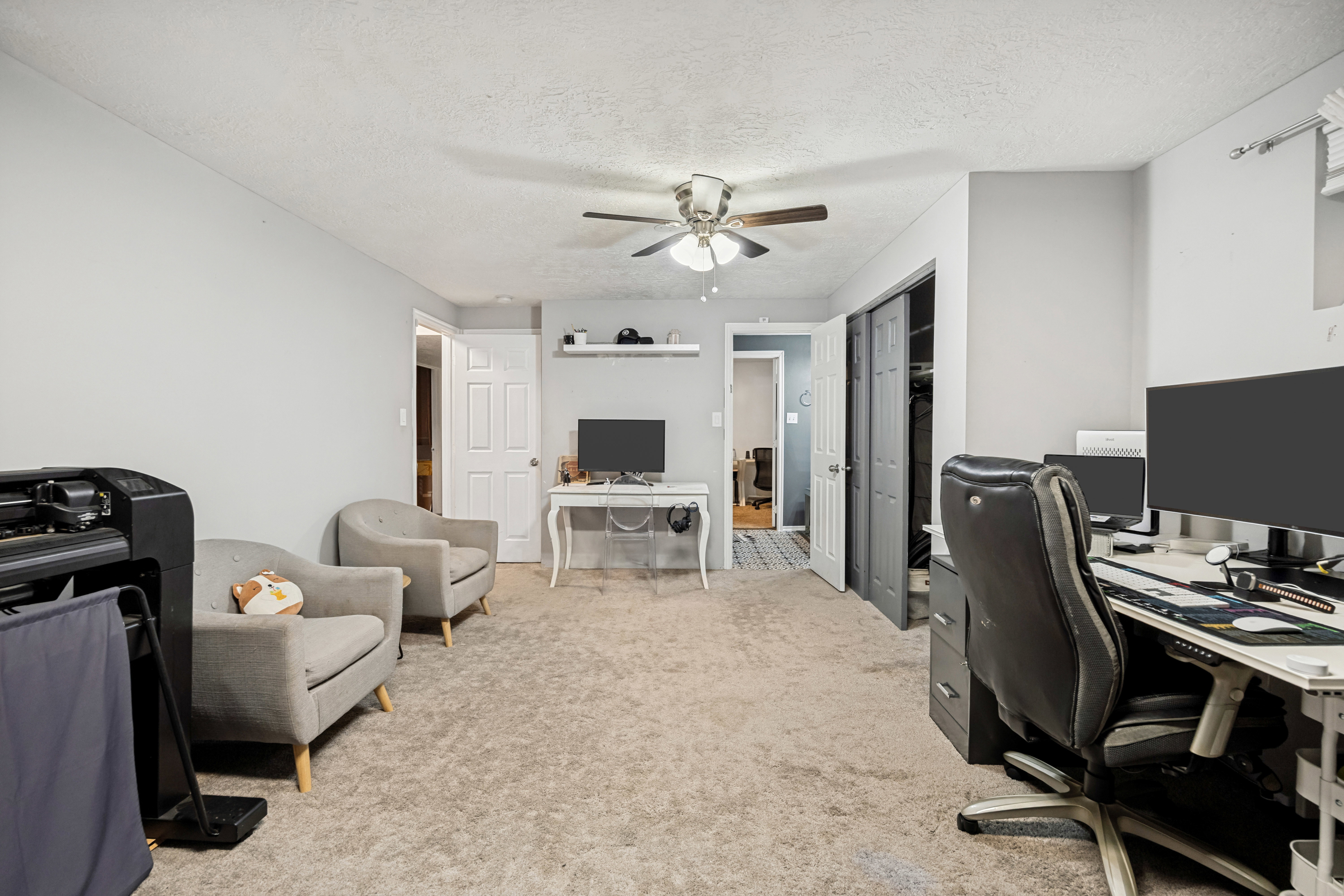 Carpeted interior room featuring light gray wall paint and a ceiling fan with light fixture