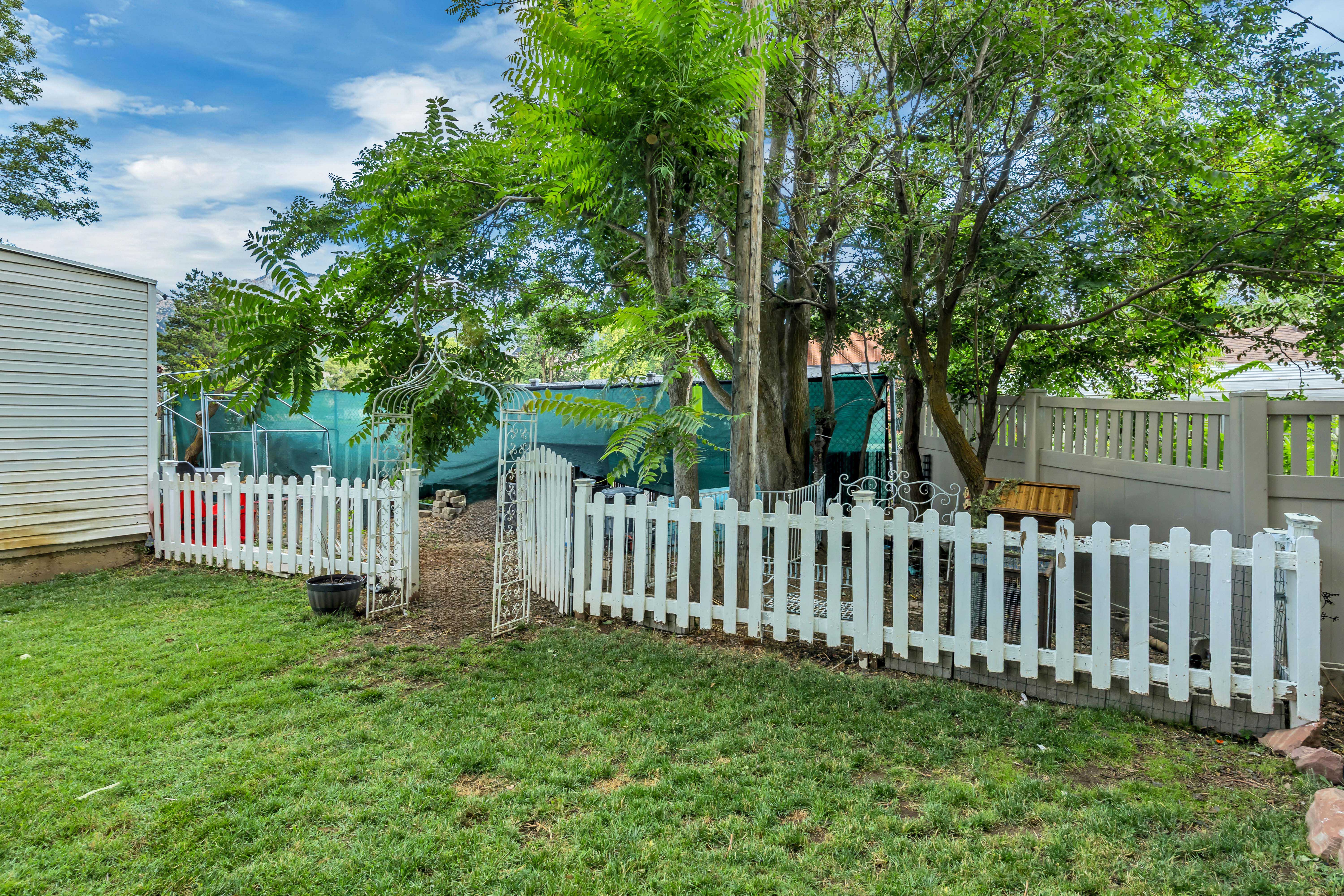 Expansive lawn area featuring a classic white picket fence with an arched gate