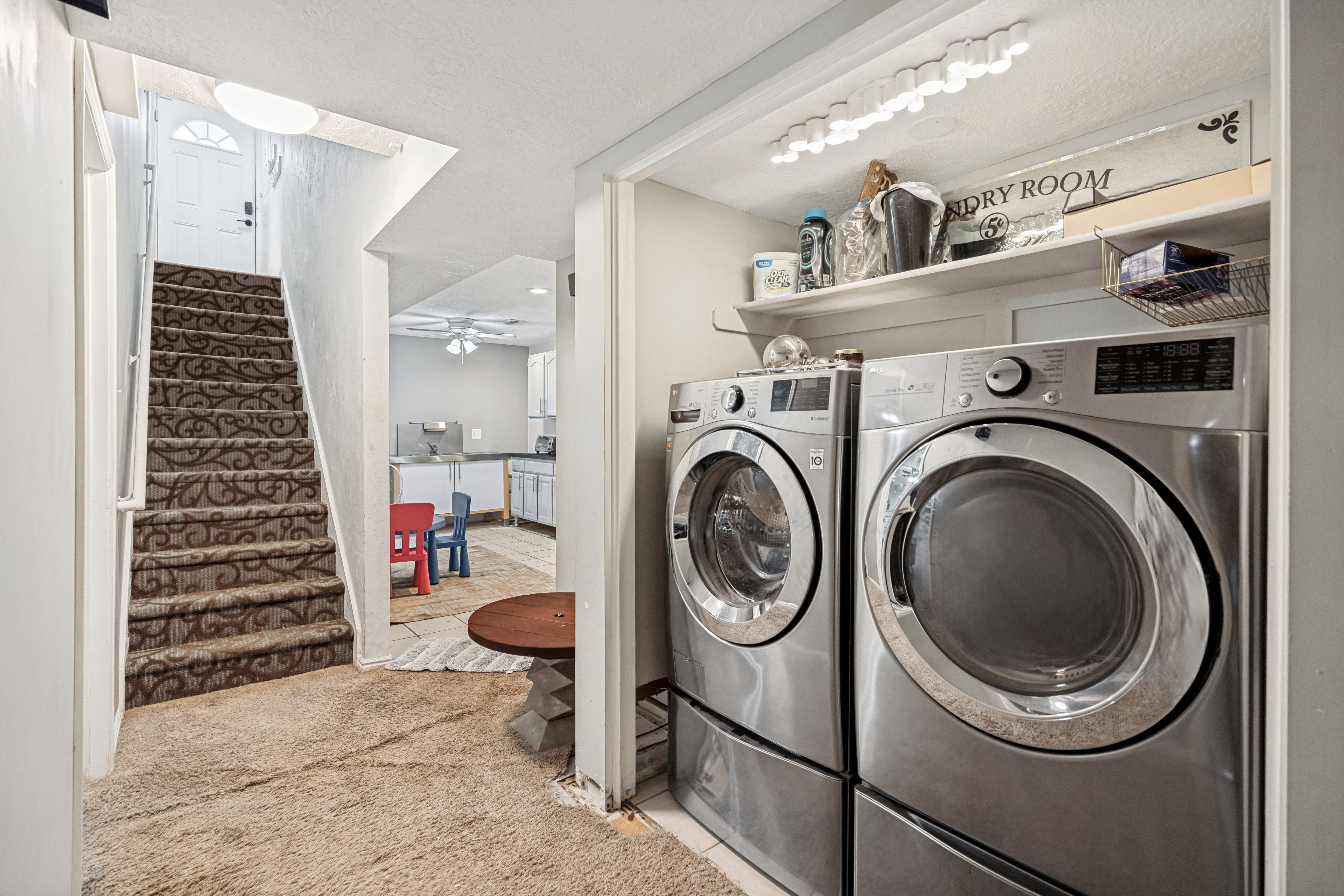 Dedicated laundry area featuring front-loading washer and dryer units with storage shelving above