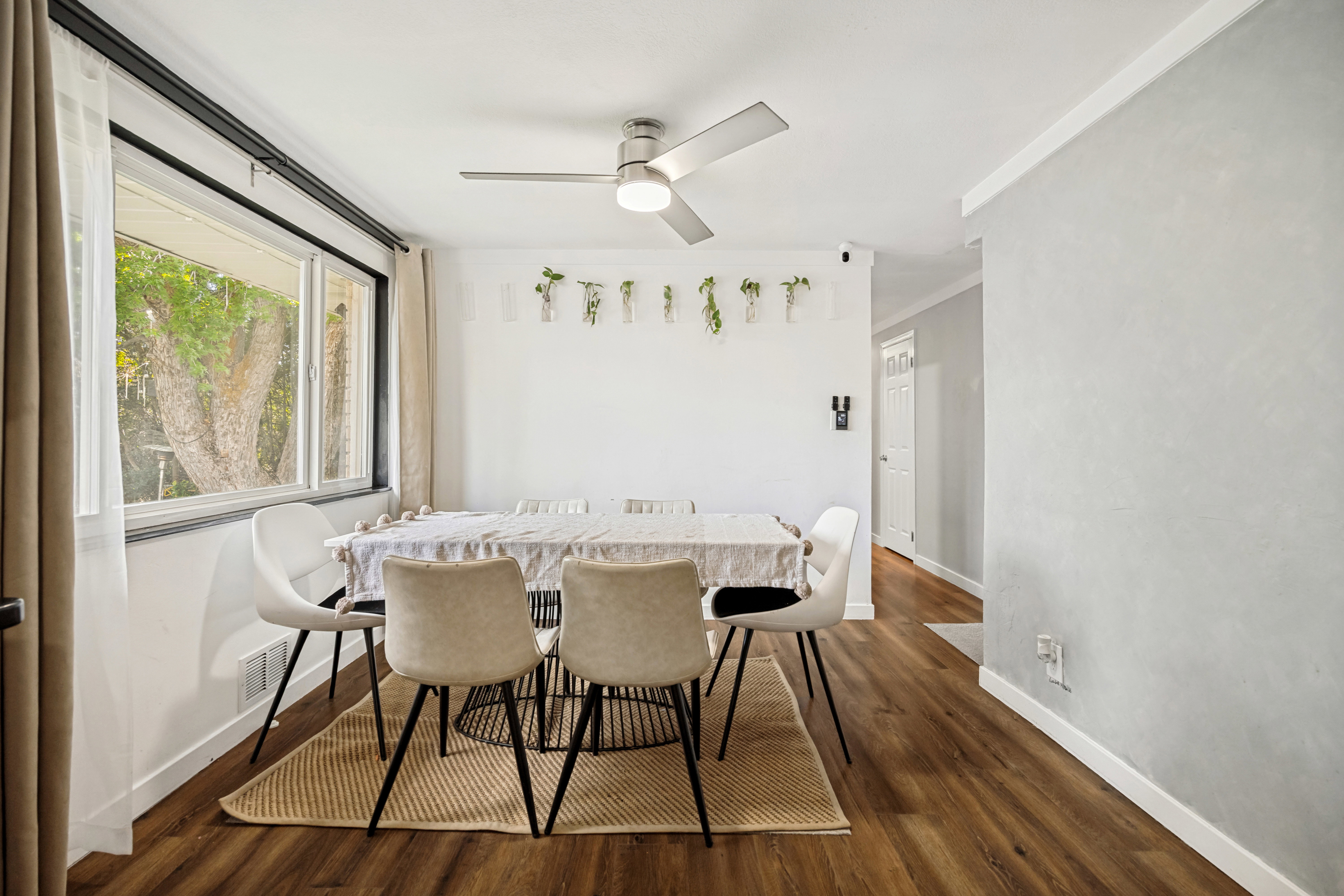 Dining area featuring wood-finish flooring, a large window, a ceiling fan with integrated lighting, and crown molding