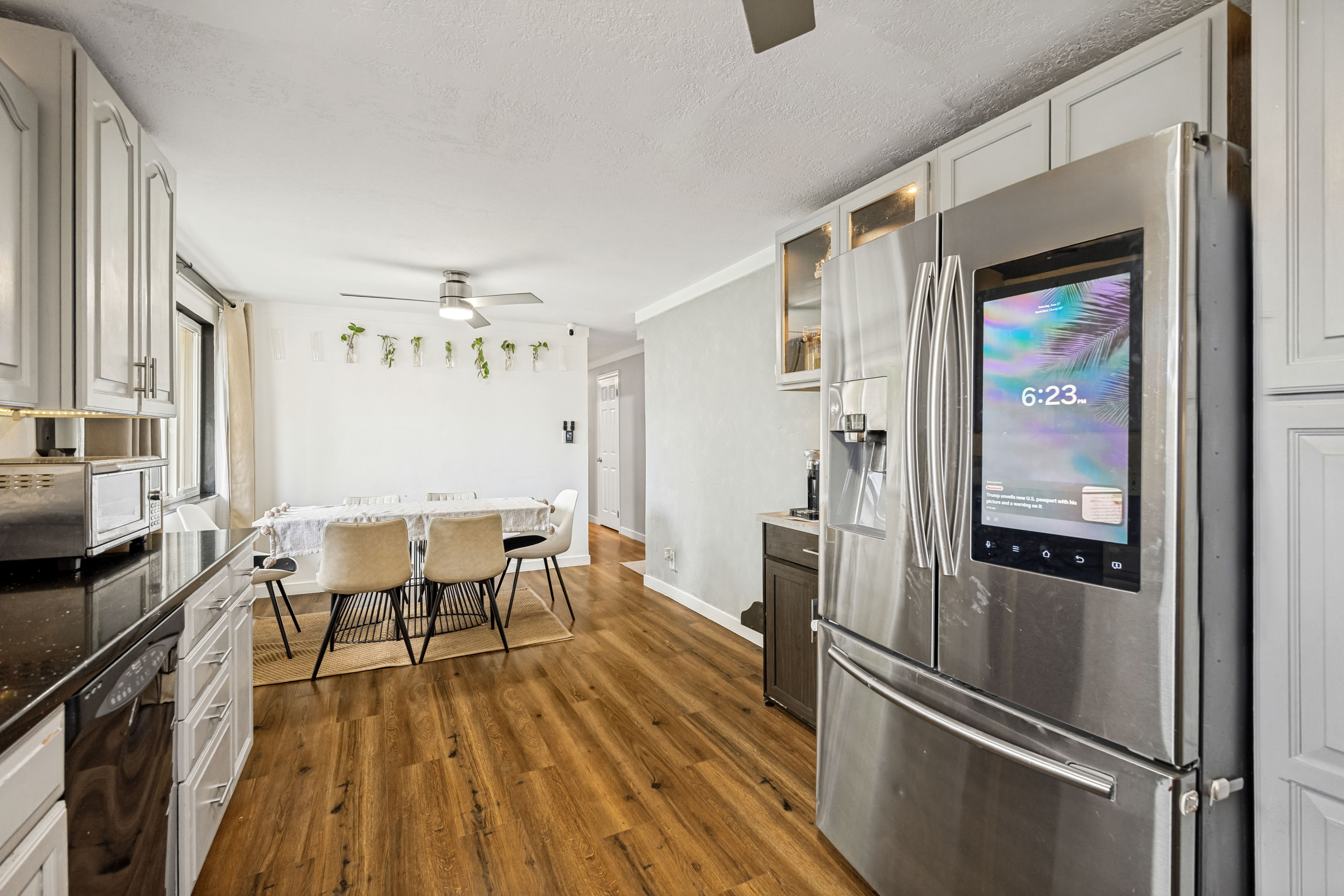Kitchen area featuring stainless steel appliances, wood-finish flooring, white cabinetry, dark countertops, and a dining space