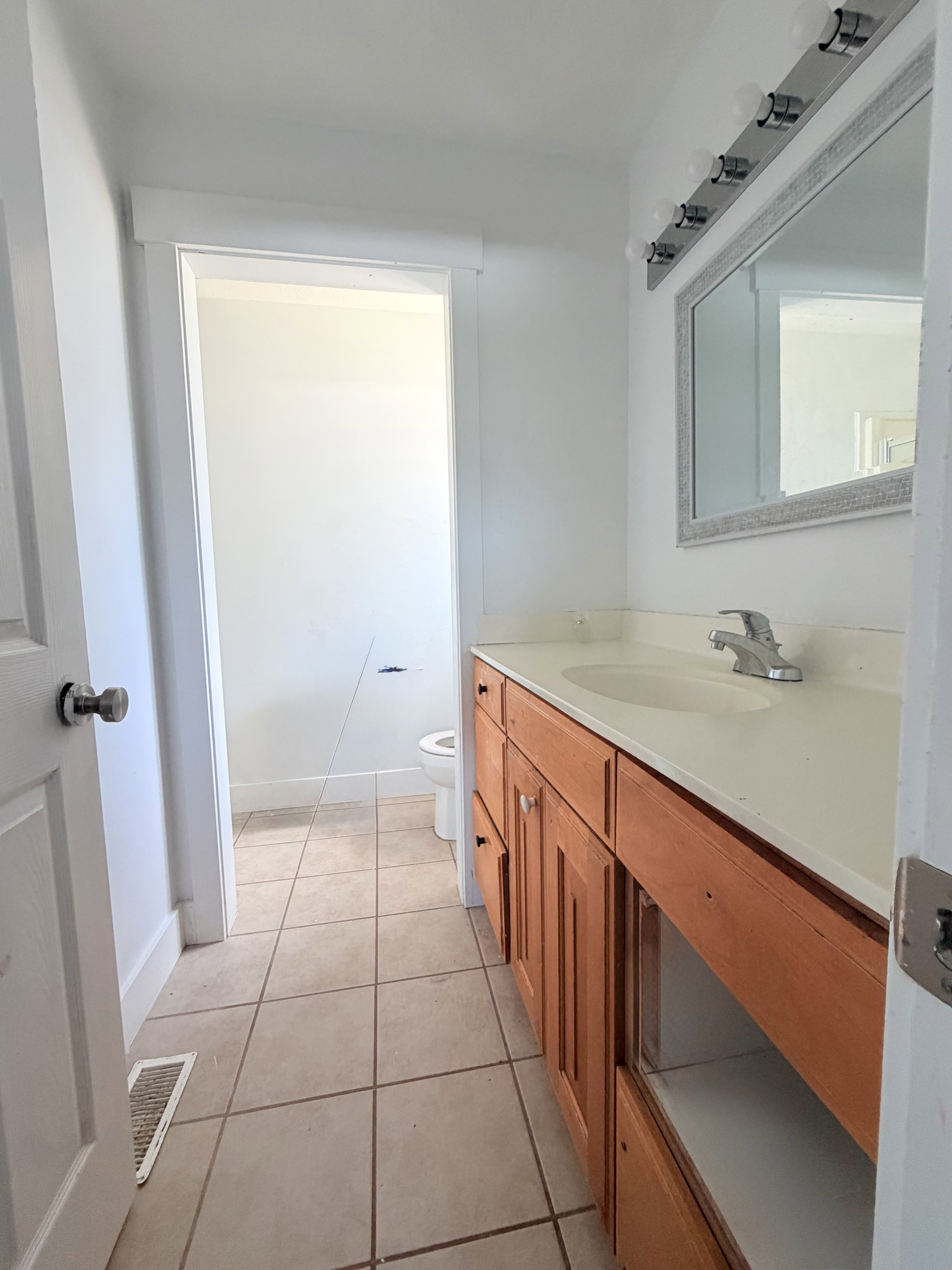 Bathroom vanity featuring wood-finish cabinetry, a single basin sink, and a light-colored countertop