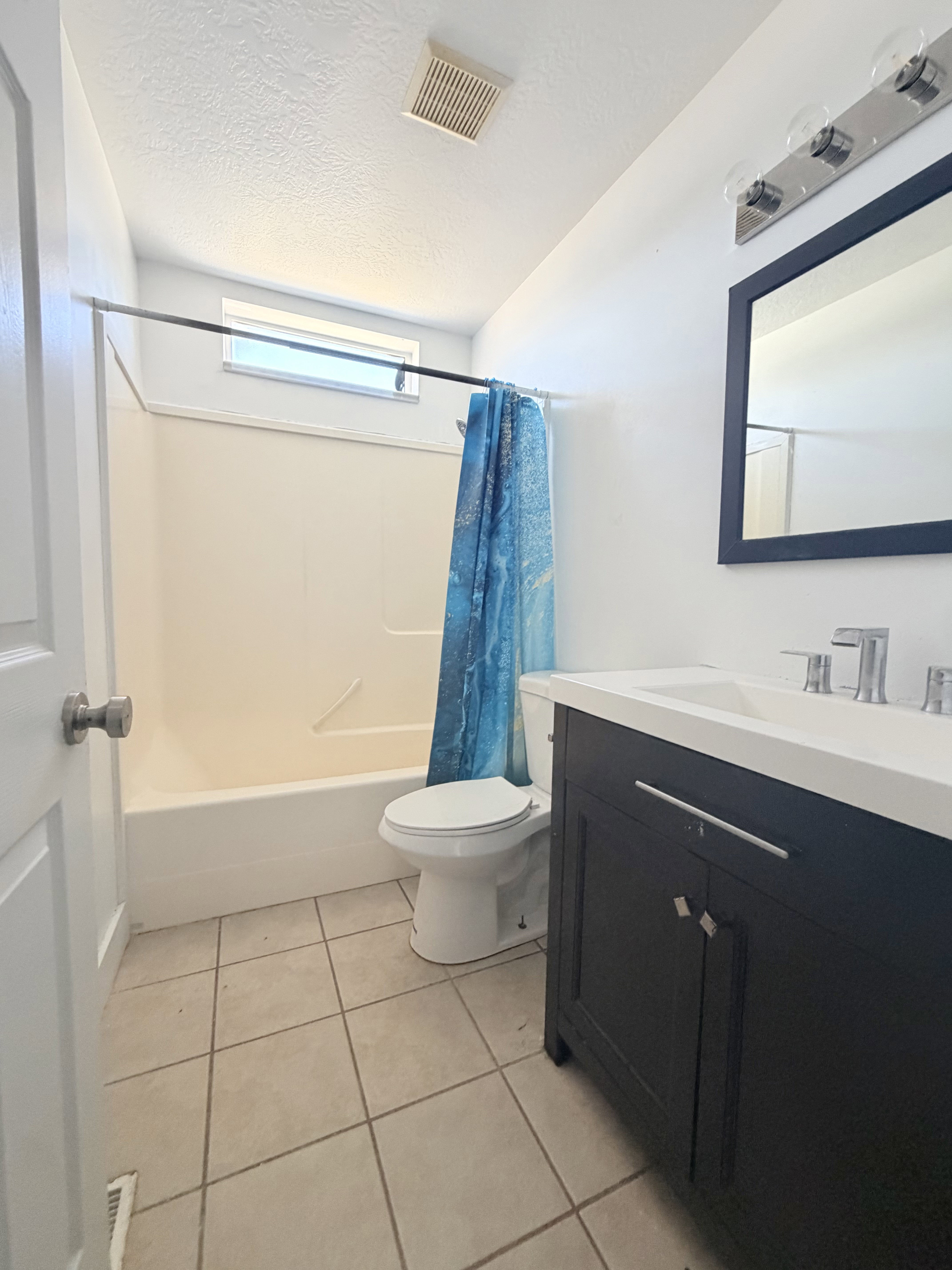 Bathroom featuring a dark wood vanity with a white countertop, chrome fixtures, and a framed mirror