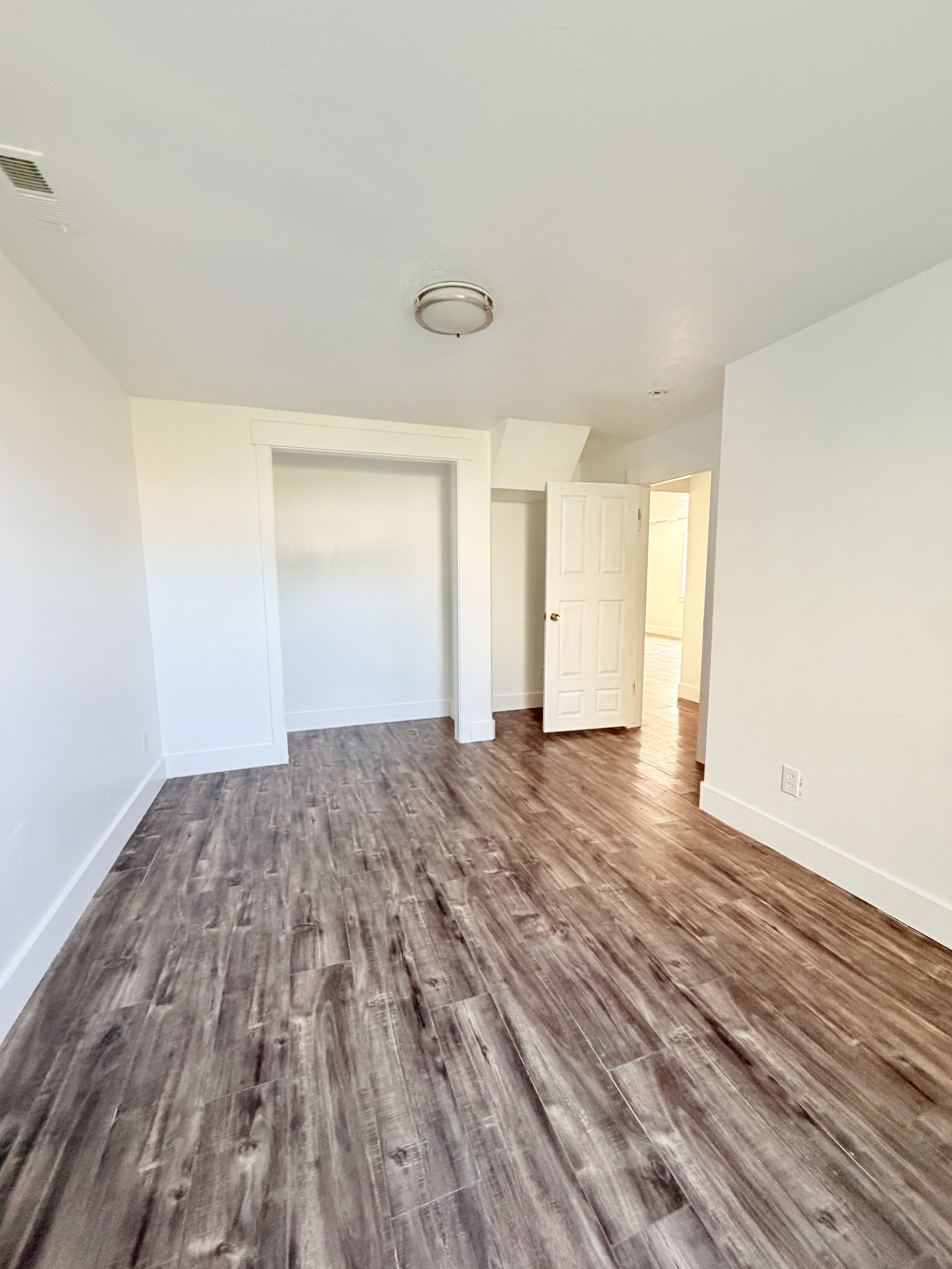 Room featuring wood-finish flooring, white baseboards, and a neutral color palette