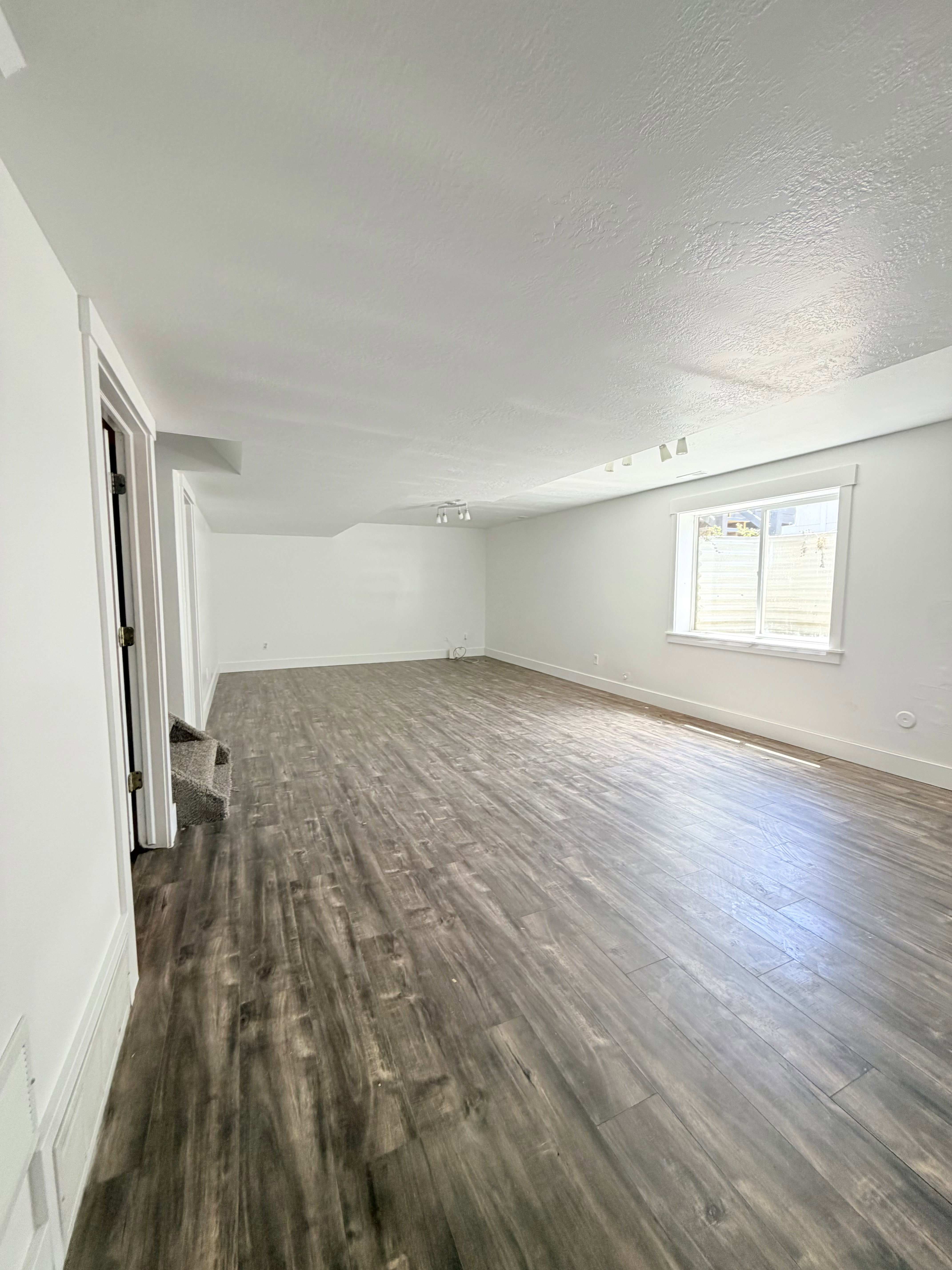 Spacious interior featuring wood-finish flooring, white walls, and a recessed window