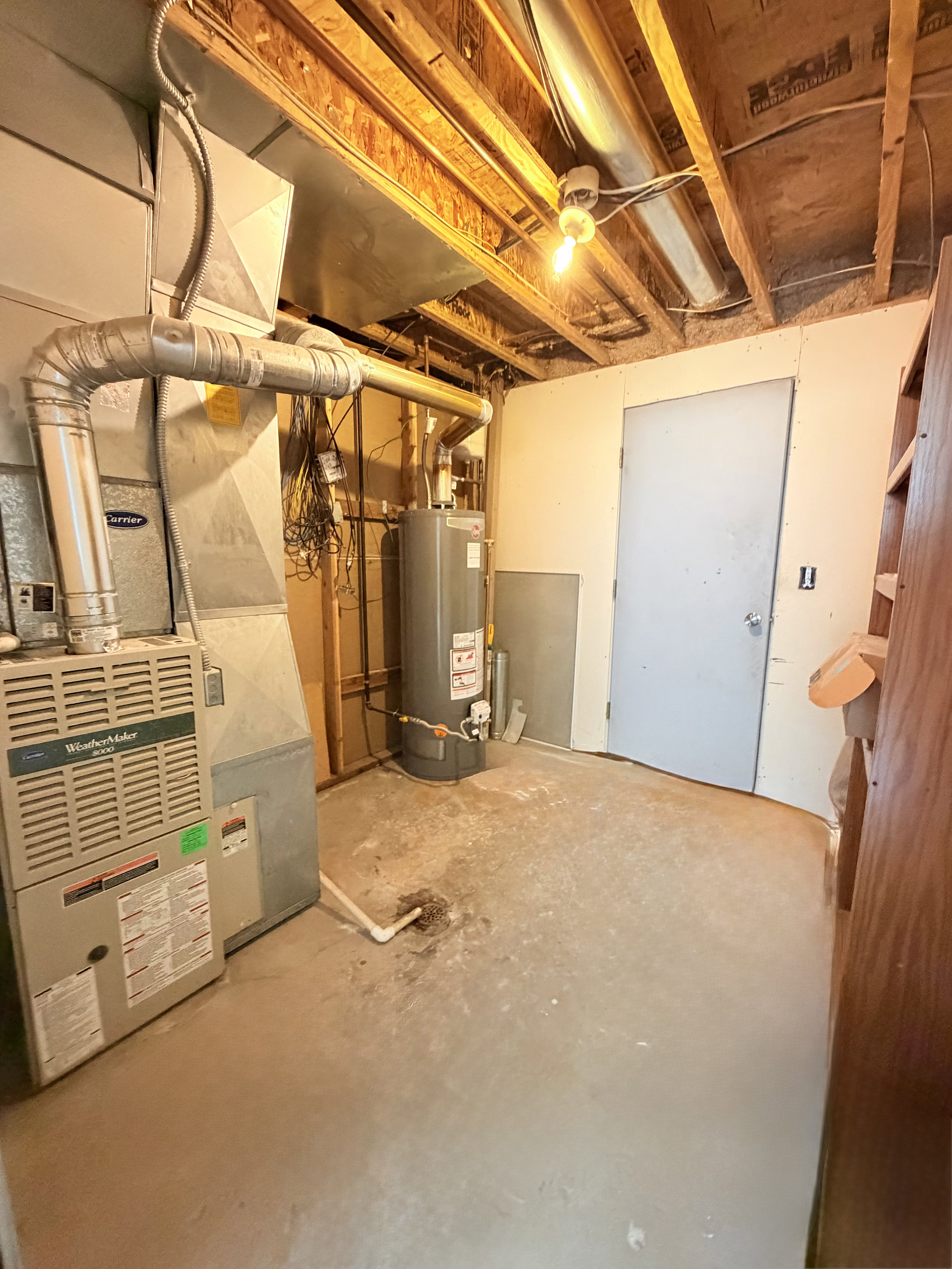 Utility room featuring a furnace, water heater, exposed wood joists, and concrete flooring