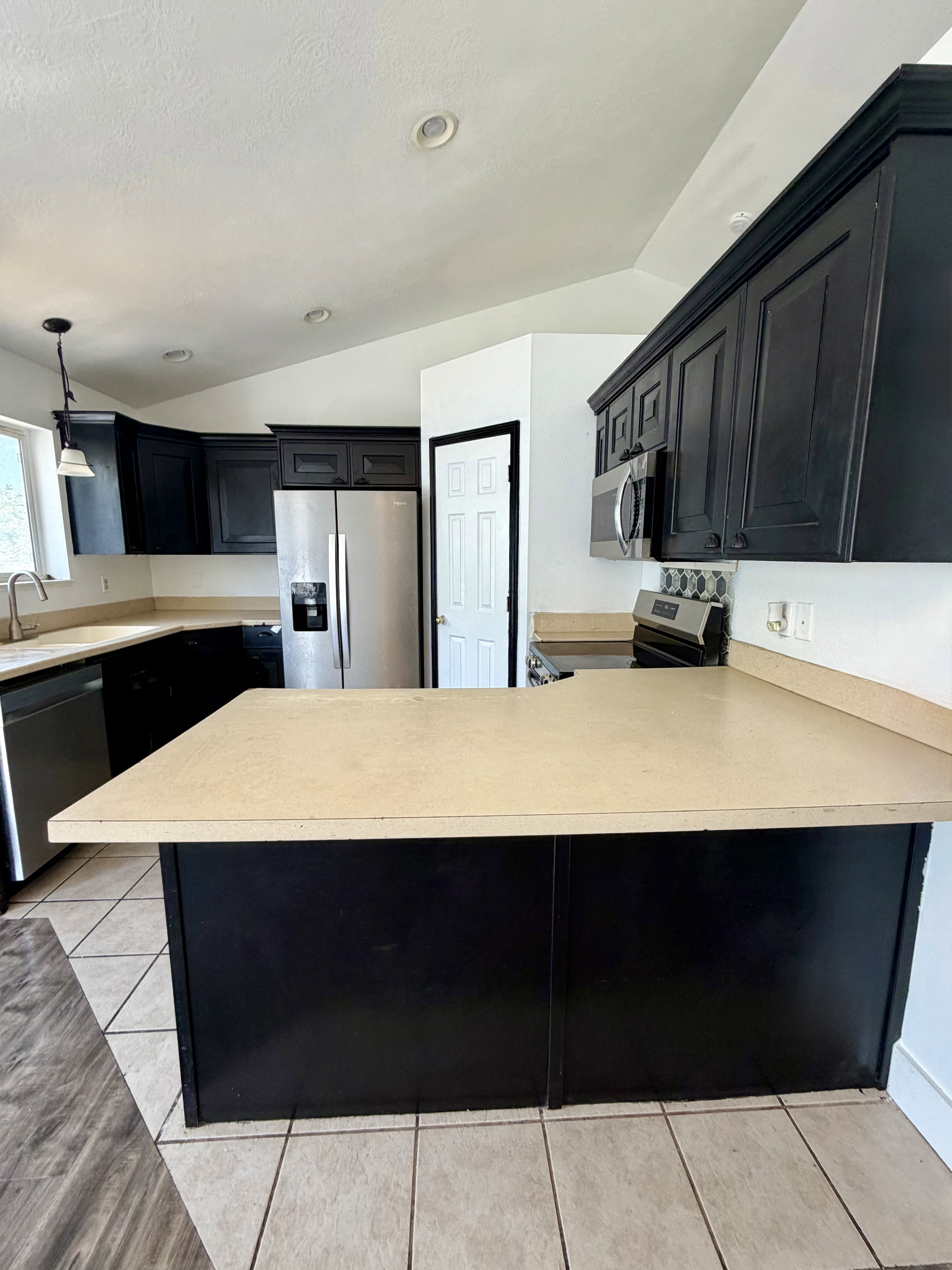 Kitchen featuring black cabinetry, light-toned countertops, and stainless steel appliances