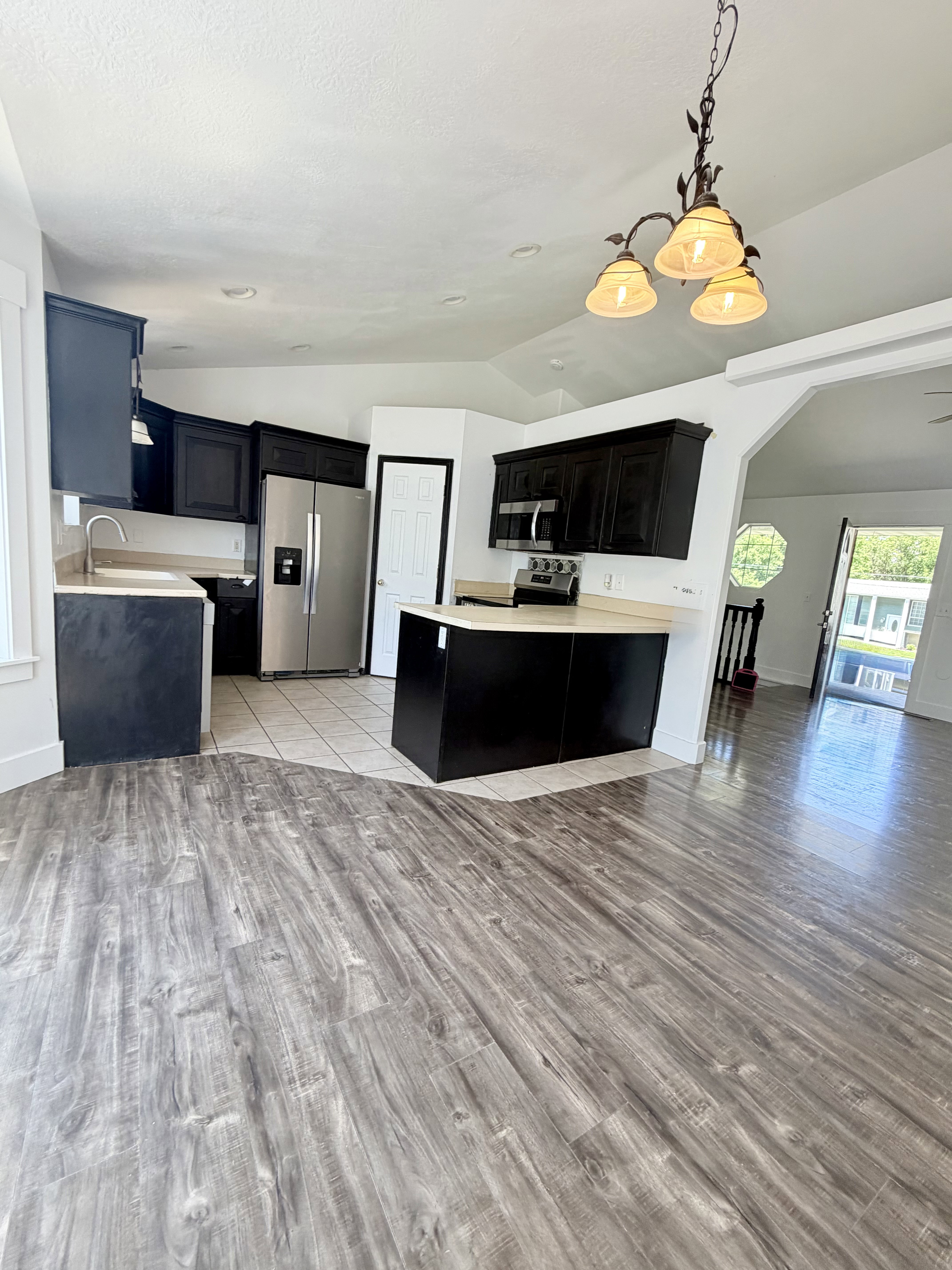 Open-concept kitchen featuring dark cabinetry, stainless steel appliances, and light-toned countertops