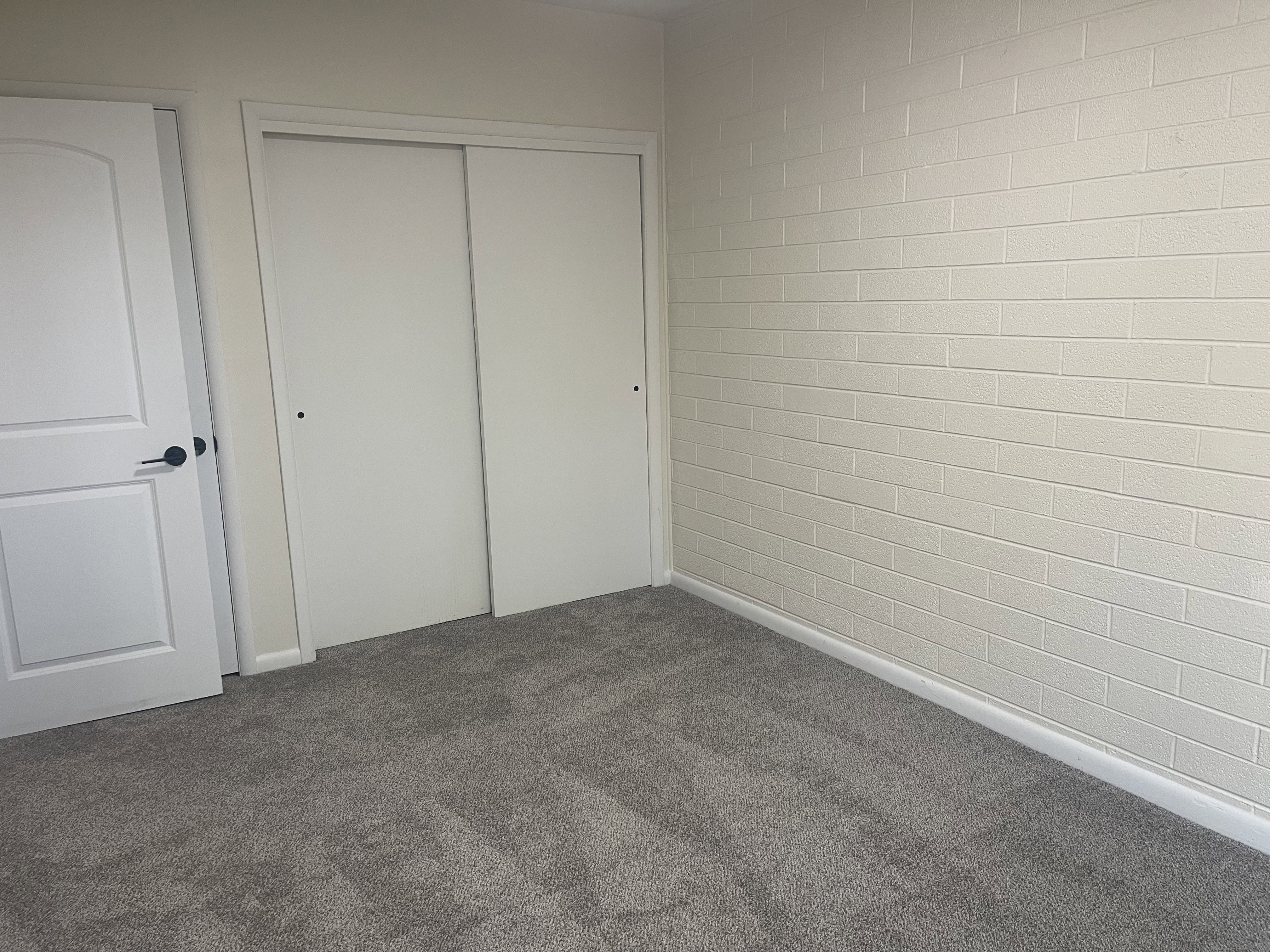 Neutral gray carpeting paired with a white brick-patterned wall