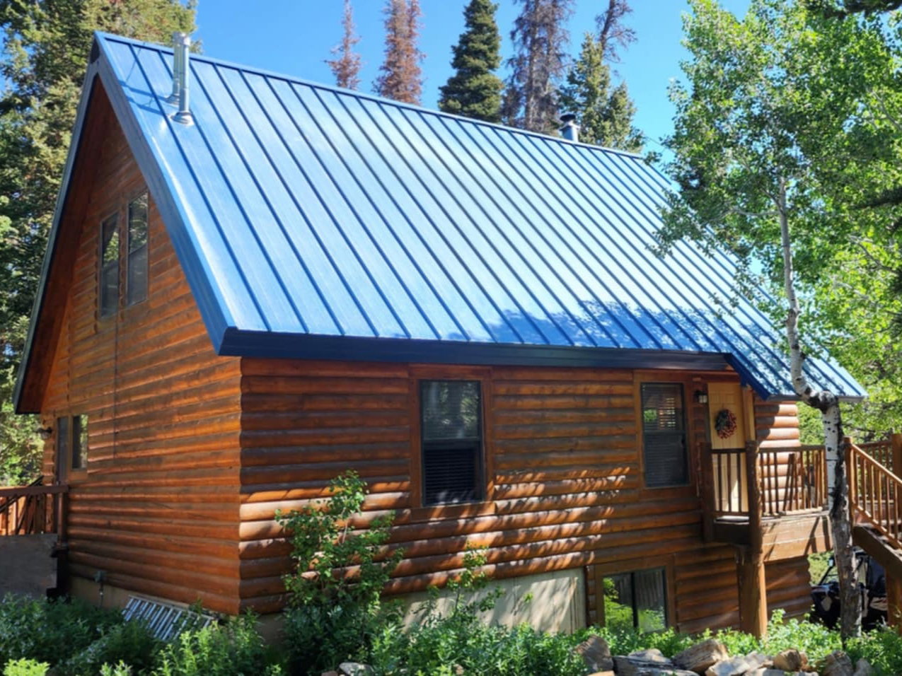 Log cabin exterior featuring a blue metal roof, an elevated wooden deck, and a multi-level staircase entry