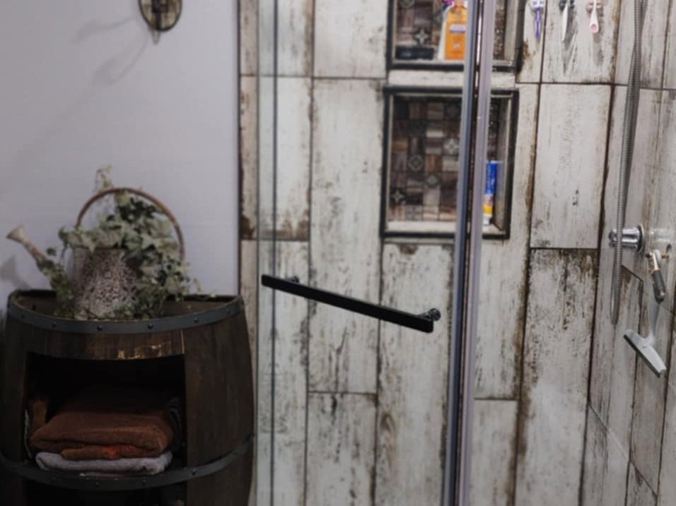 Corner glass-enclosed shower with a white base