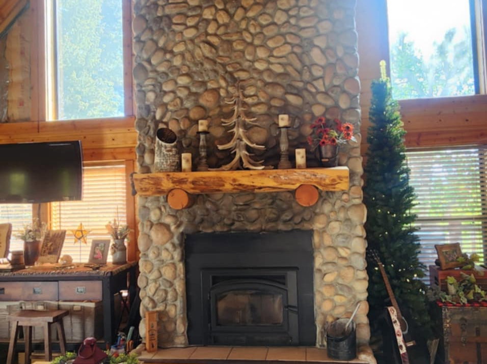 Soaring stone-clad fireplace with a natural log mantel