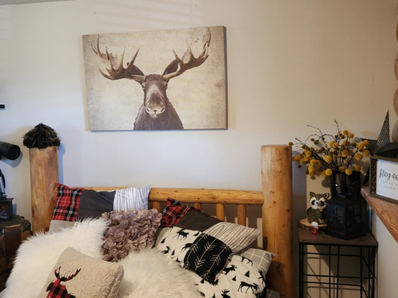 Natural wood-finish bed frame, light-toned walls, and a visible wood log structural element
