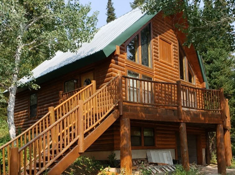 Log cabin exterior featuring a metal roof, an elevated deck, and exposed log construction
