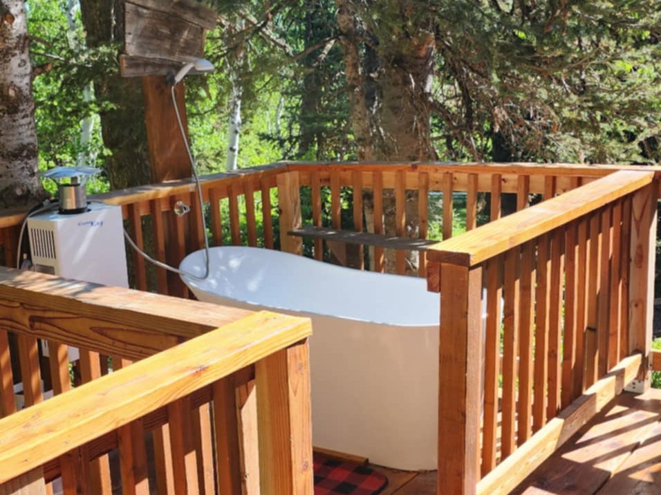 Wood-finish decking with a built-in outdoor bathtub, surrounded by natural wood railing