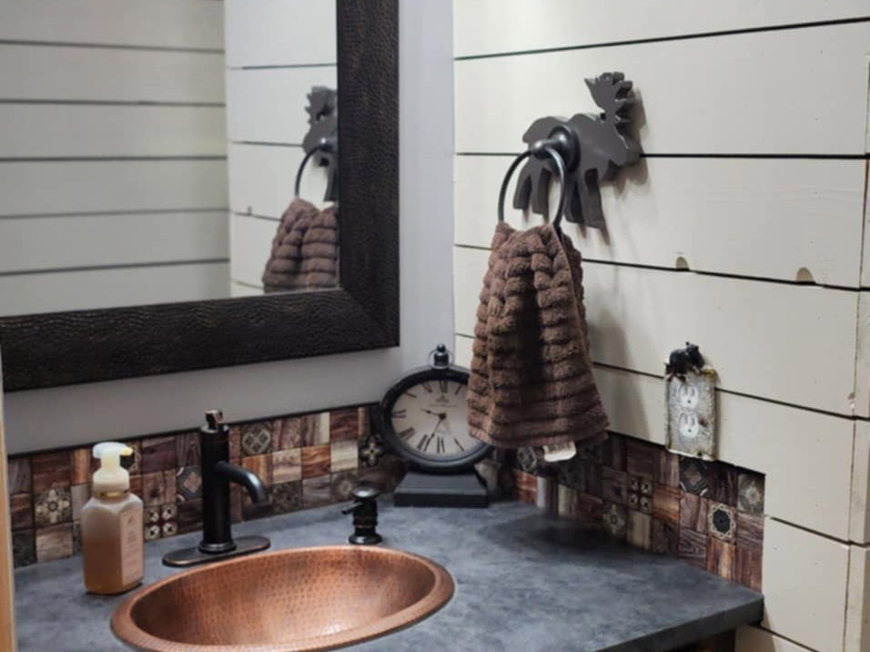 Bathroom featuring a copper vessel sink, dark countertop, and wood-finish cabinetry