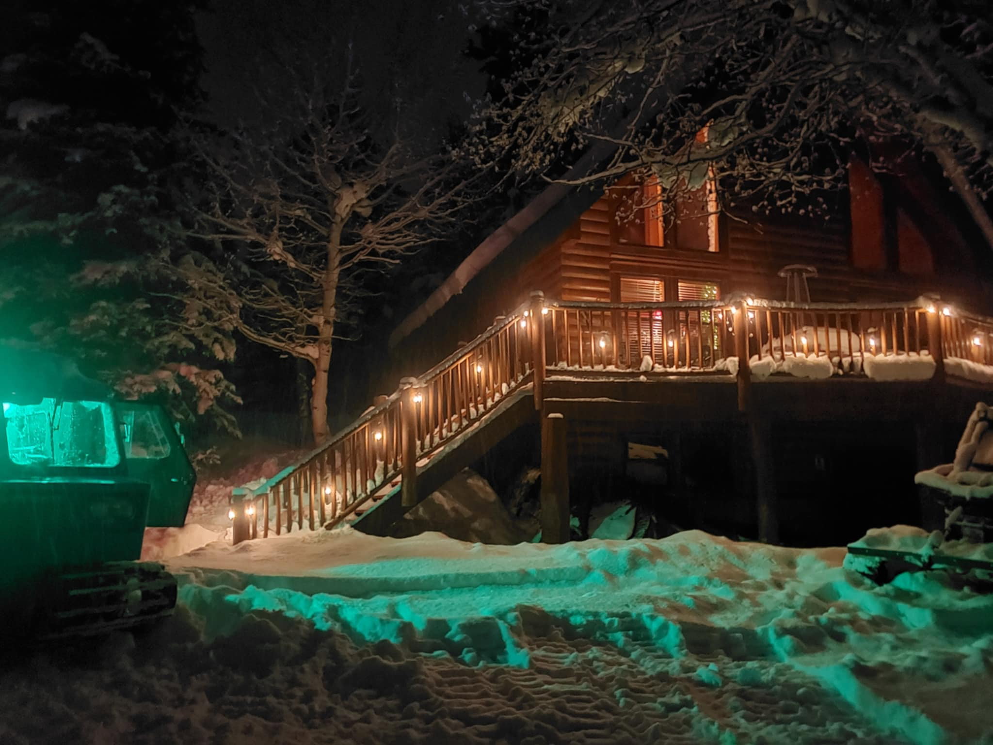 Log cabin exterior featuring a multi-level deck, wood railings, and an A-frame architectural style