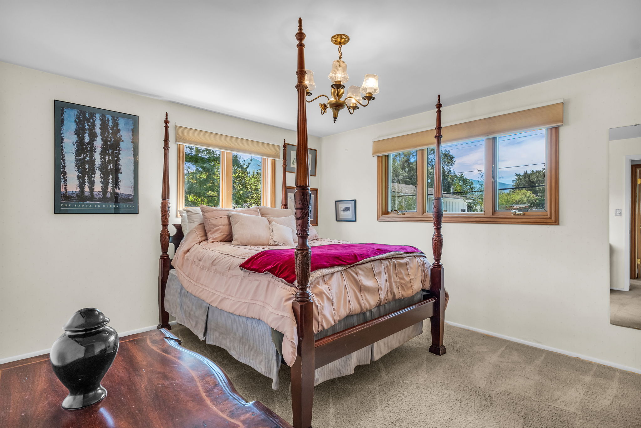 Bedroom featuring two large windows, carpet flooring, and a brass chandelier