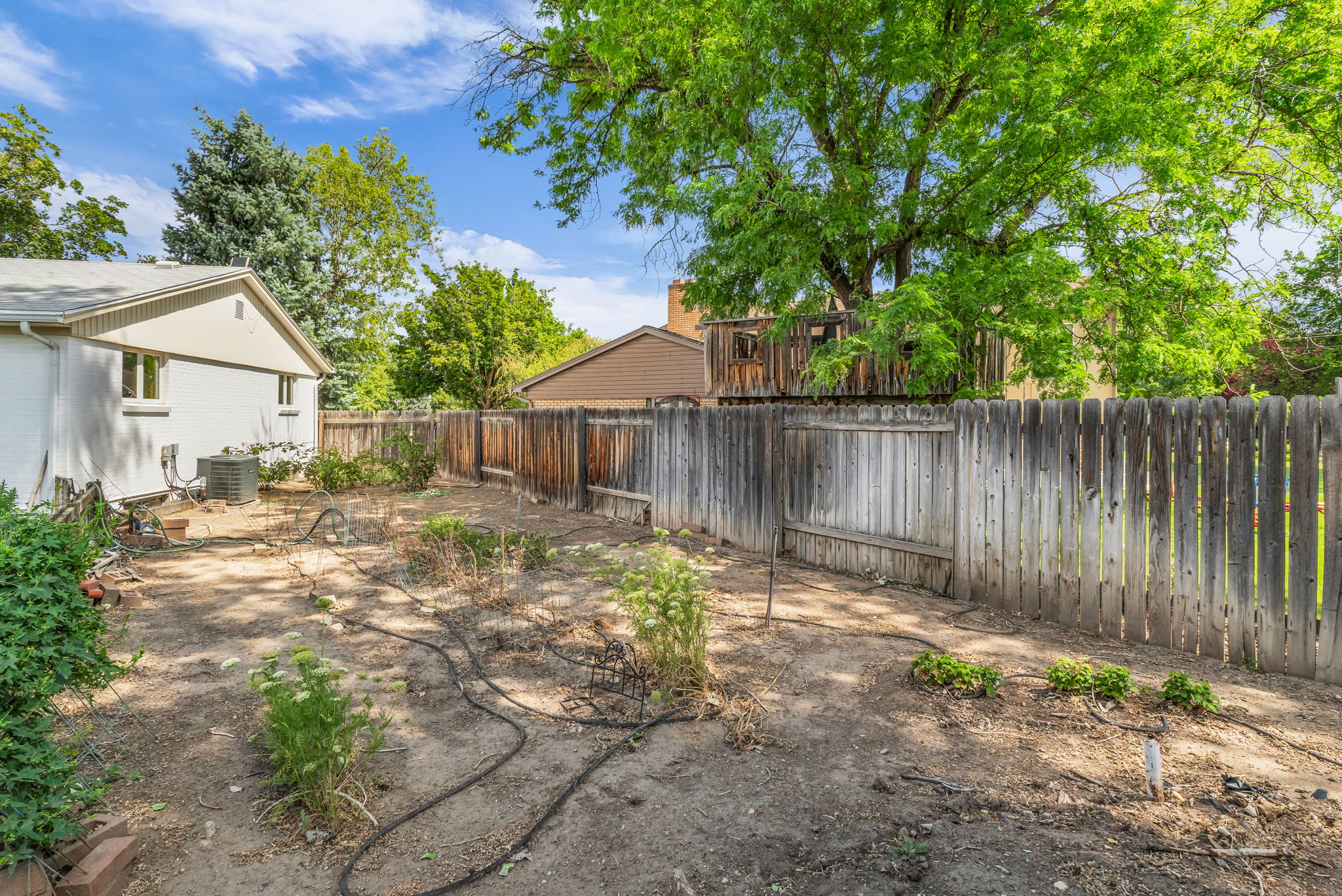 Expansive backyard area featuring a wood privacy fence and mature trees