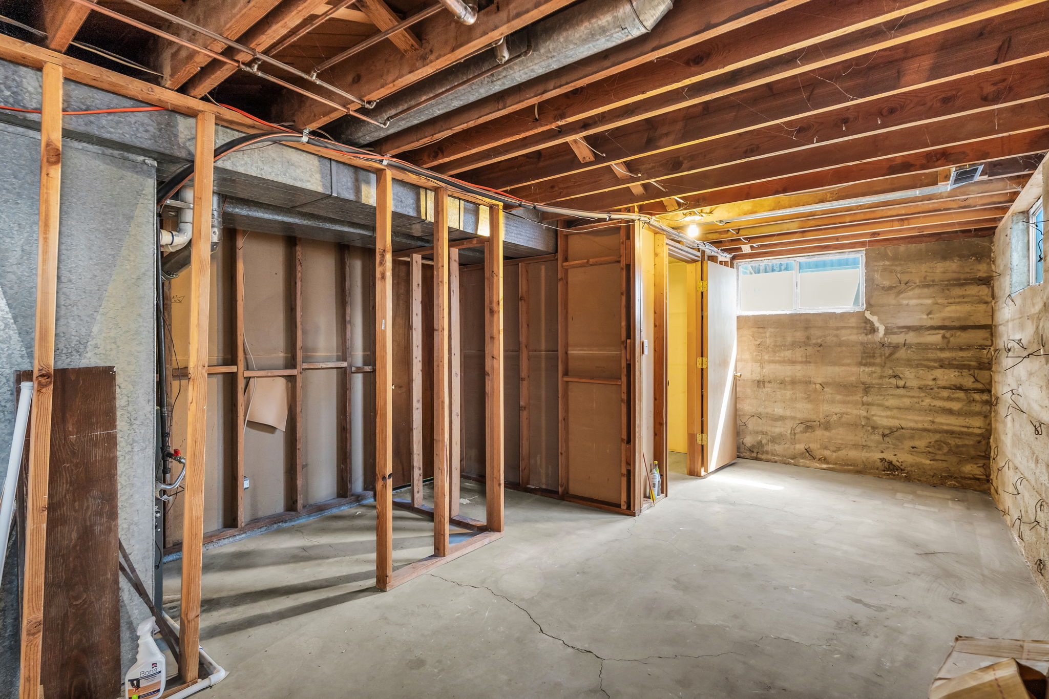 Unfinished lower level featuring exposed wood joists and concrete flooring