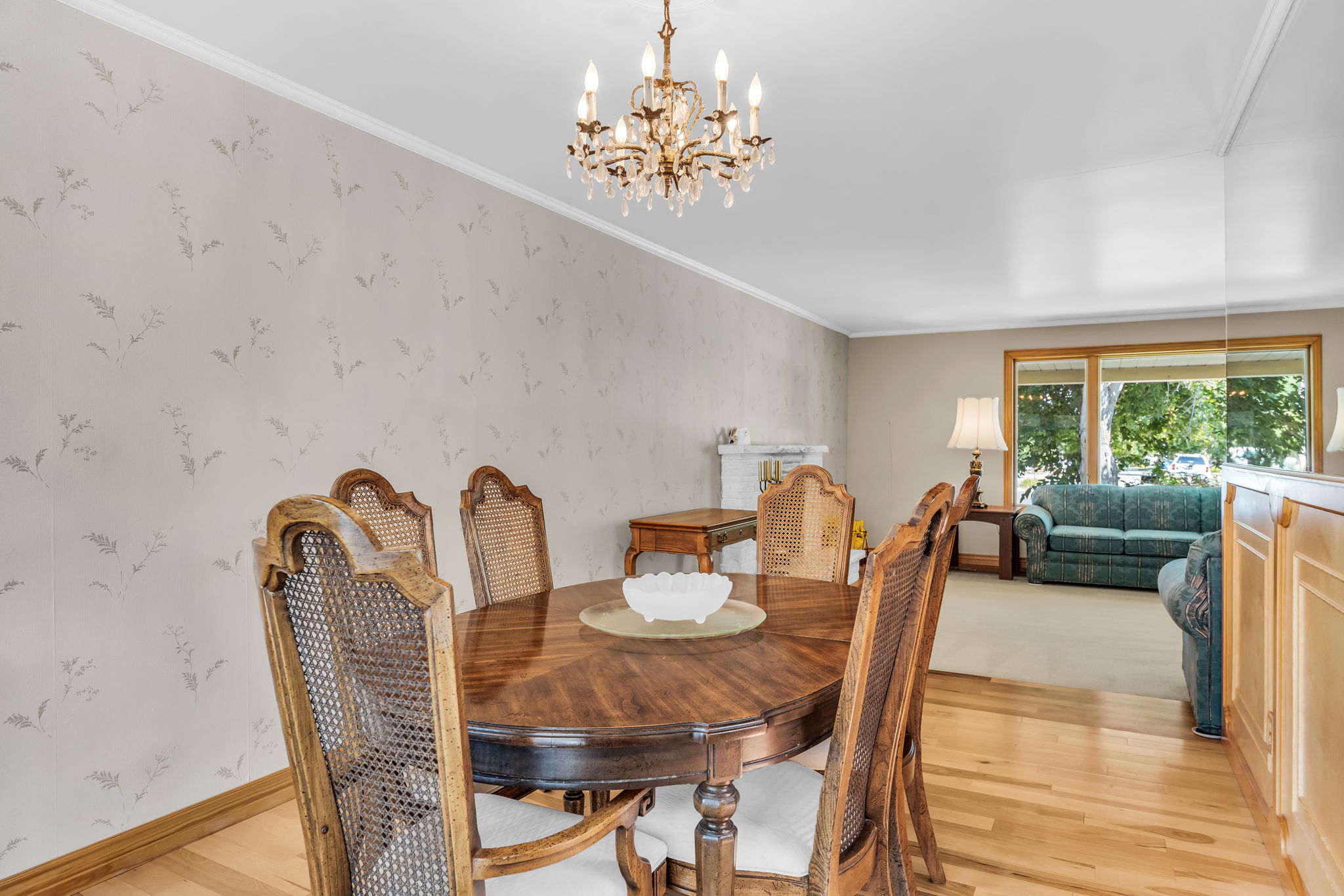 Formal dining area featuring wood-finish flooring, patterned accent wall, and a crystal chandelier