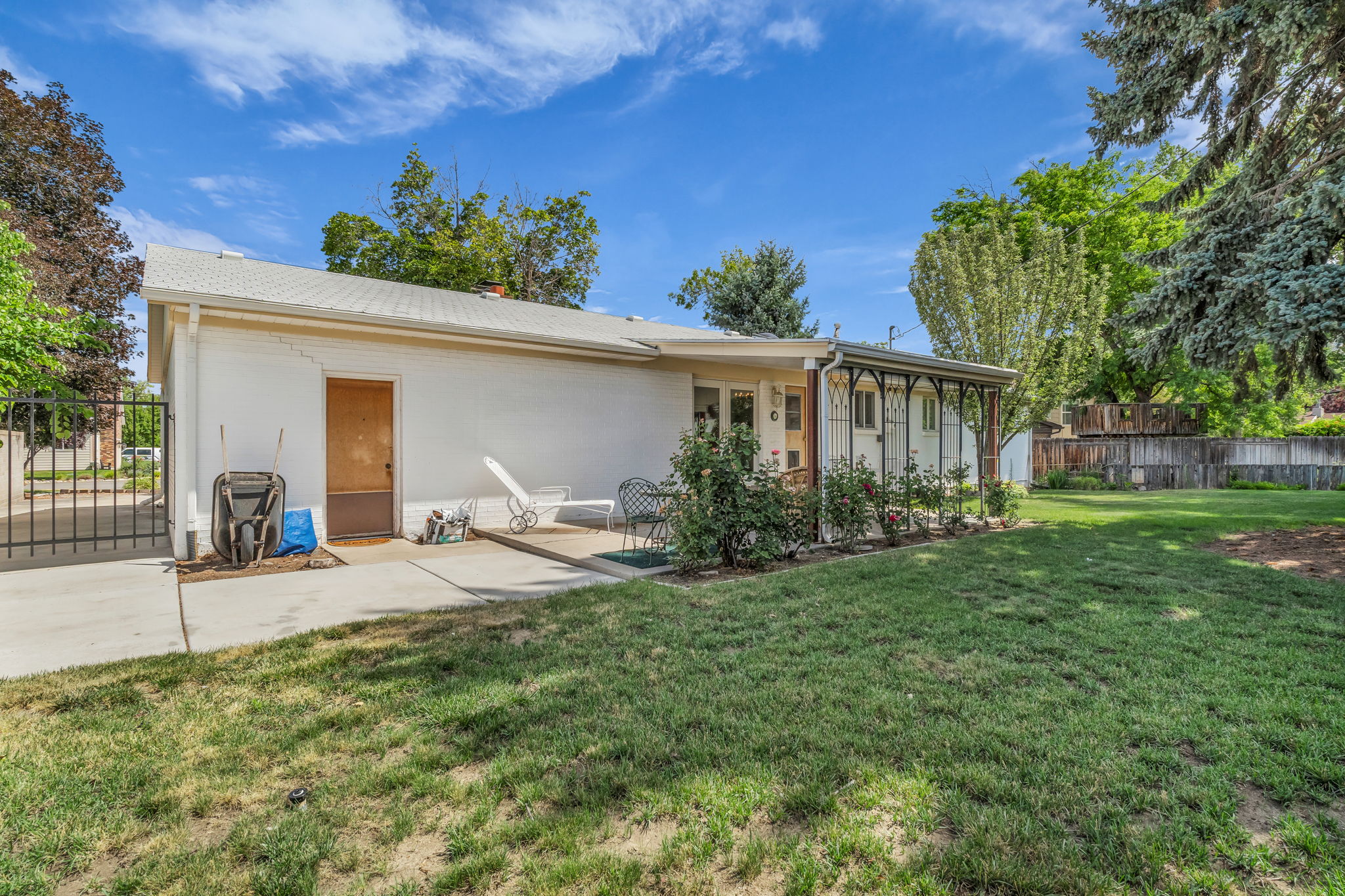 Spacious side yard featuring a lush lawn, mature perimeter trees, and a concrete patio