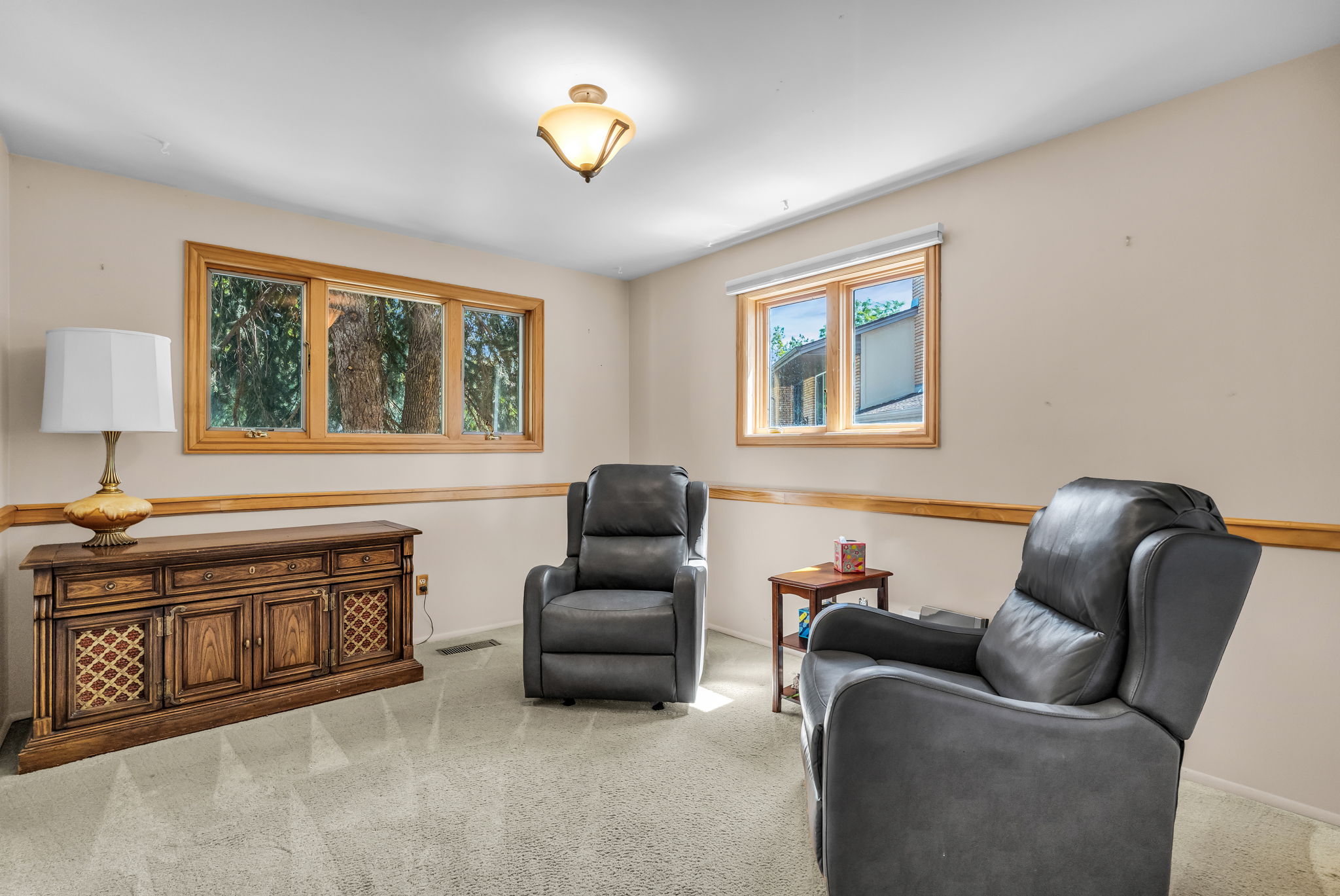 Bright room featuring neutral wall paint, light-toned carpeting, wood trim, and multiple windows