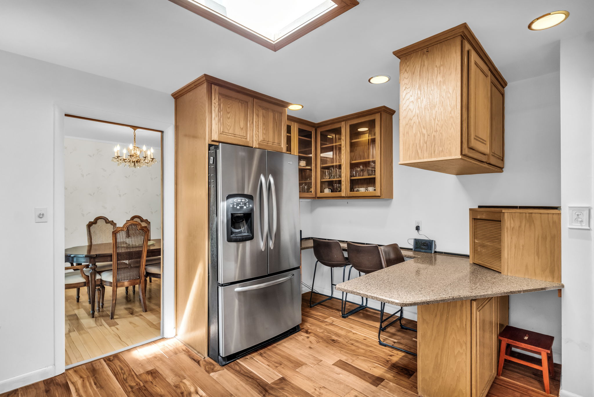 Kitchen featuring a skylight, wood-finish flooring, and built-in wood cabinetry