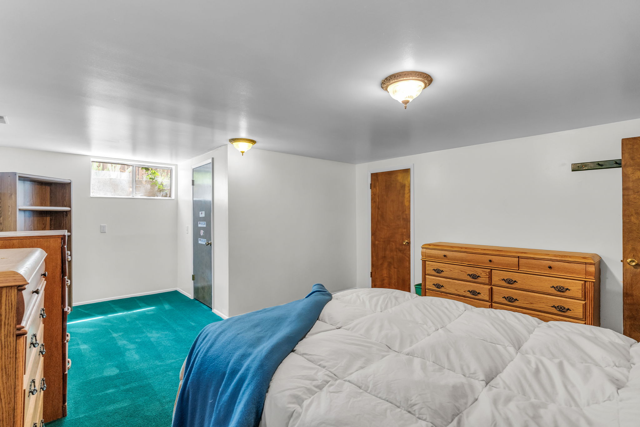Carpeted bedroom featuring white walls, a single window, and a built-in wooden bookshelf