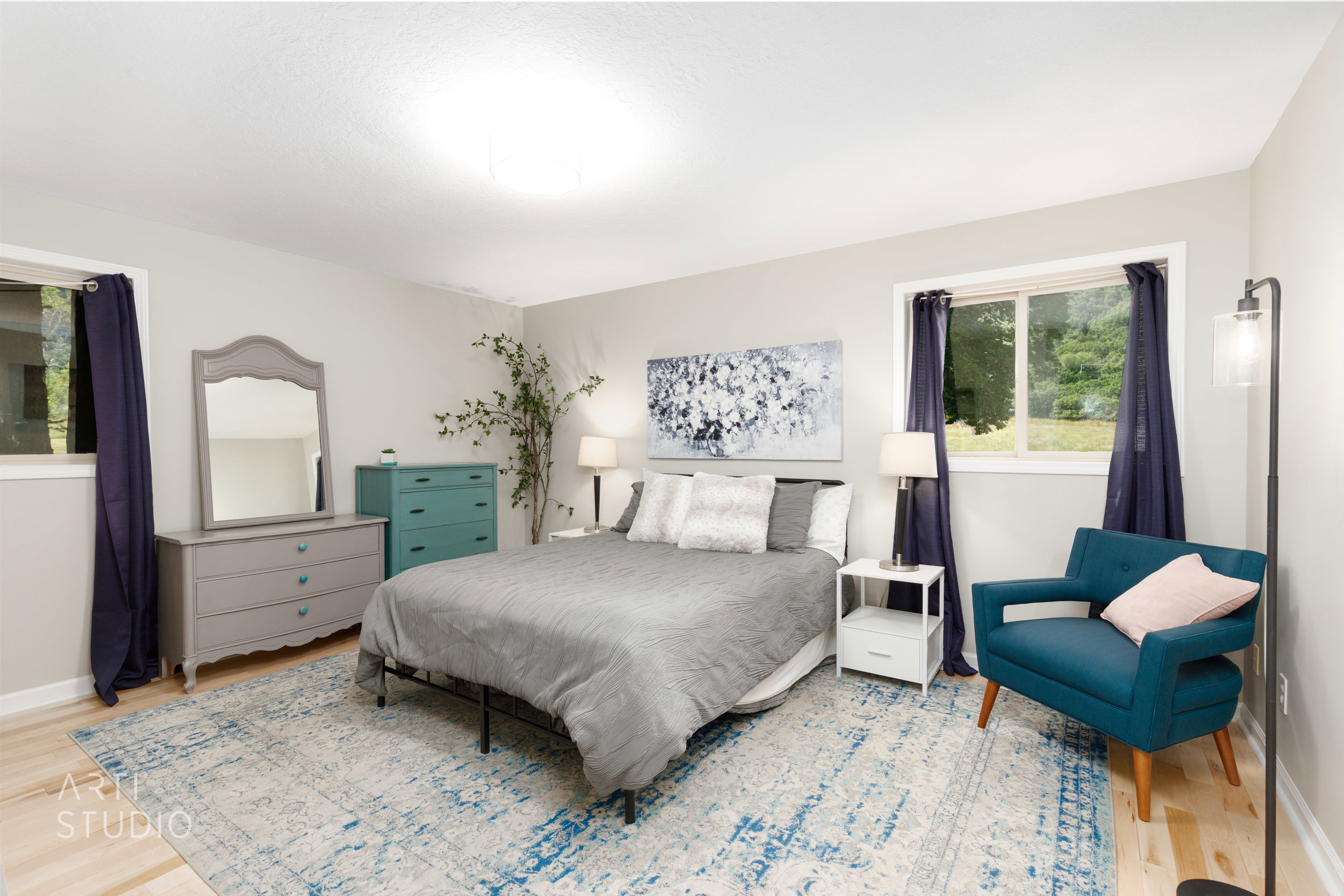 Spacious room featuring light wood-finish flooring, neutral wall tones, and two windows