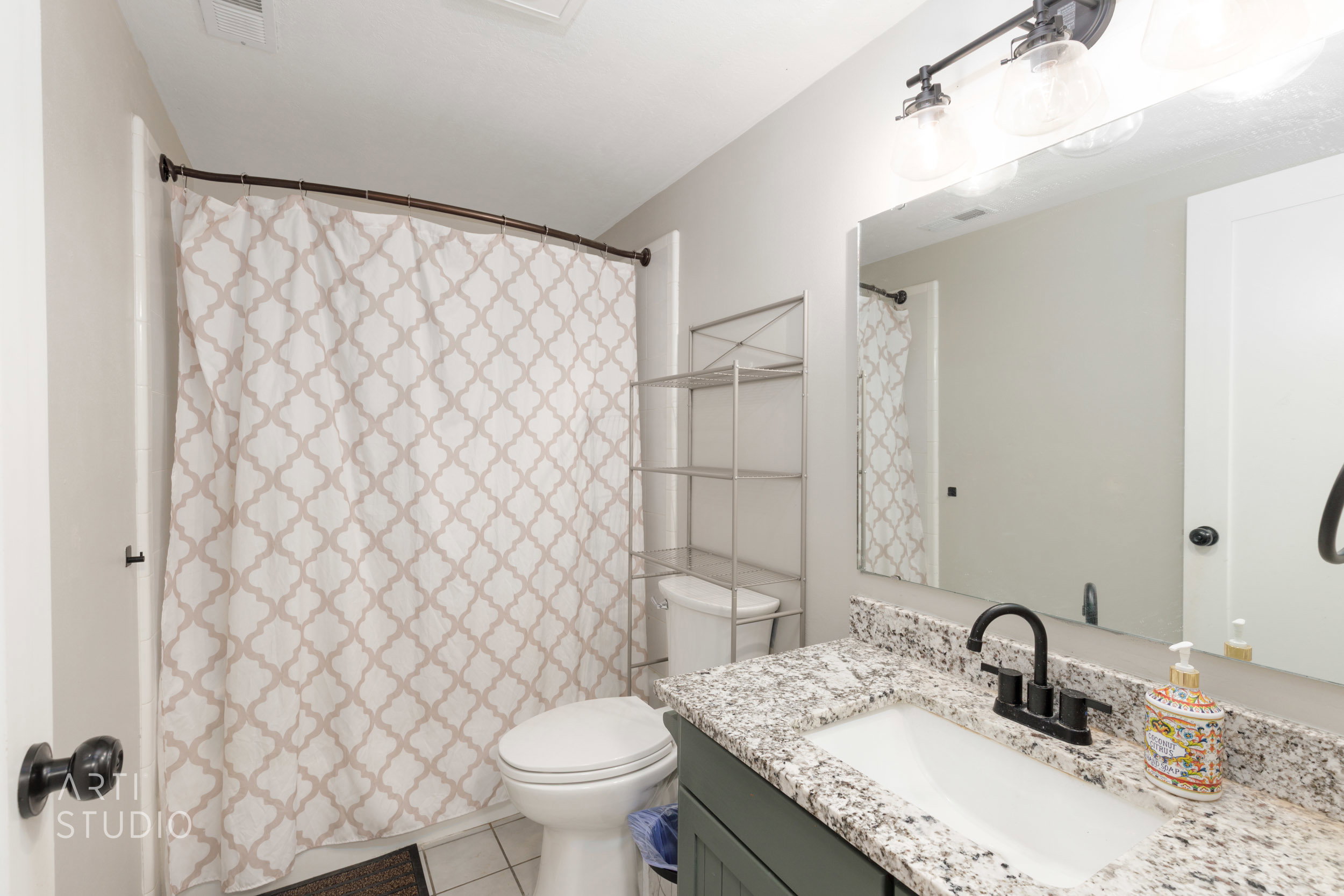Bathroom vanity featuring a speckled countertop, integrated white sink, and matte black faucet