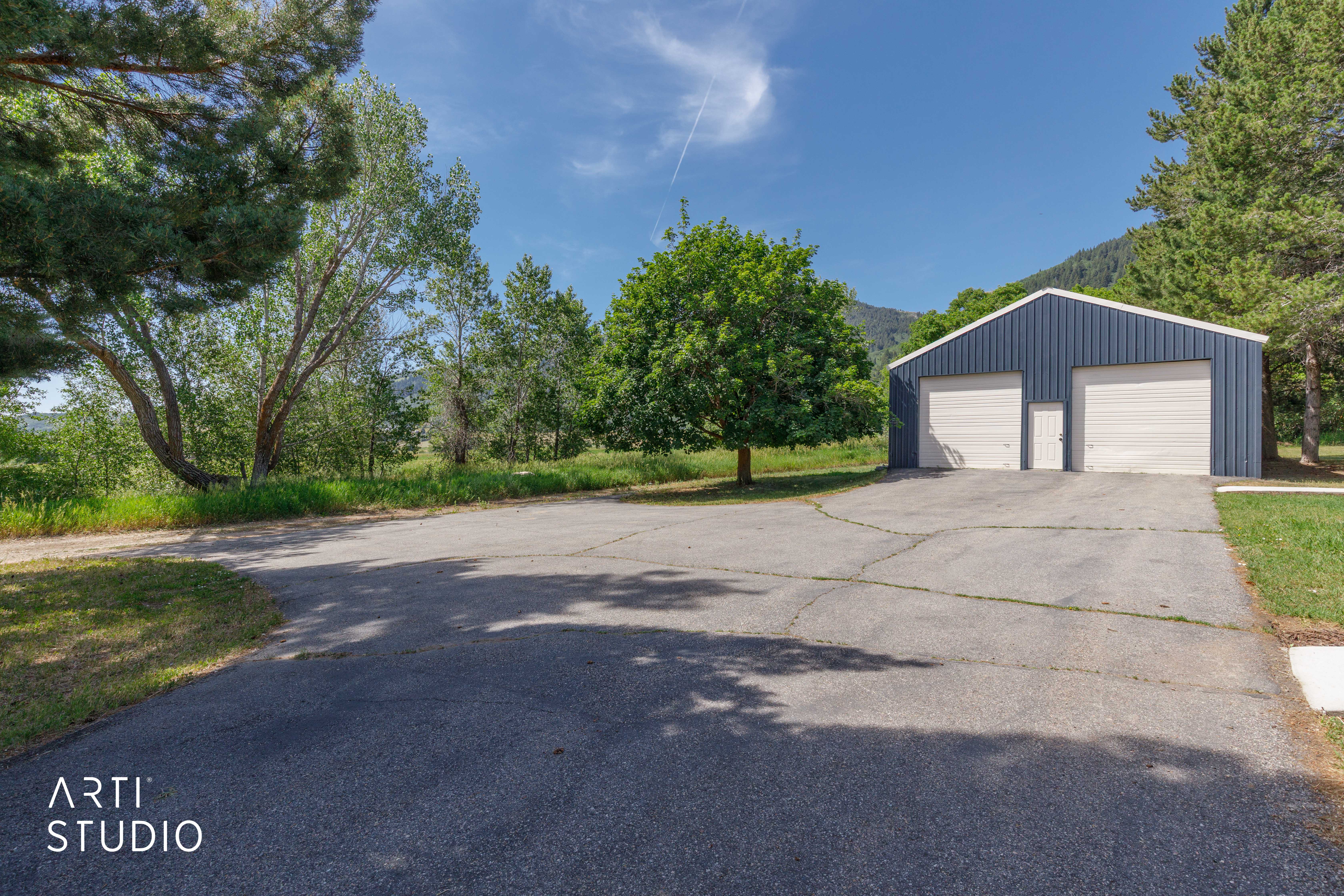 Blue metal-sided outbuilding featuring two garage doors and a single access door