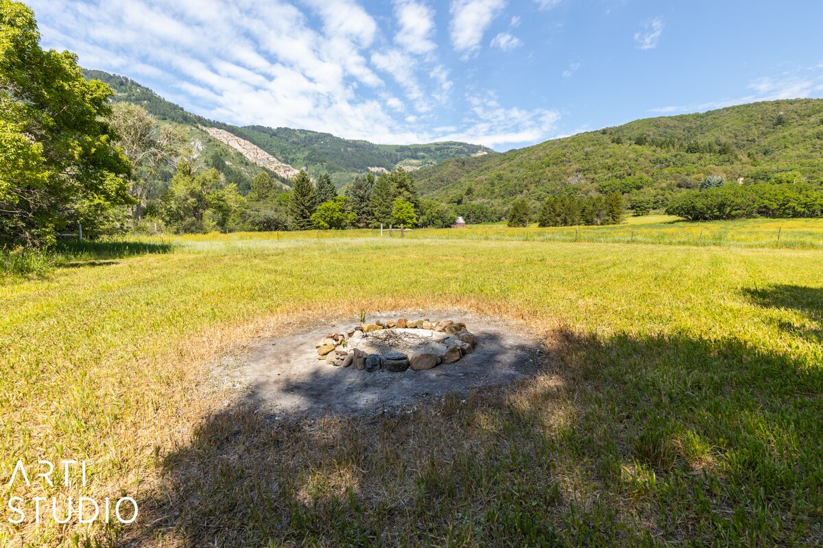 Expansive grass field featuring a stone-lined fire pit