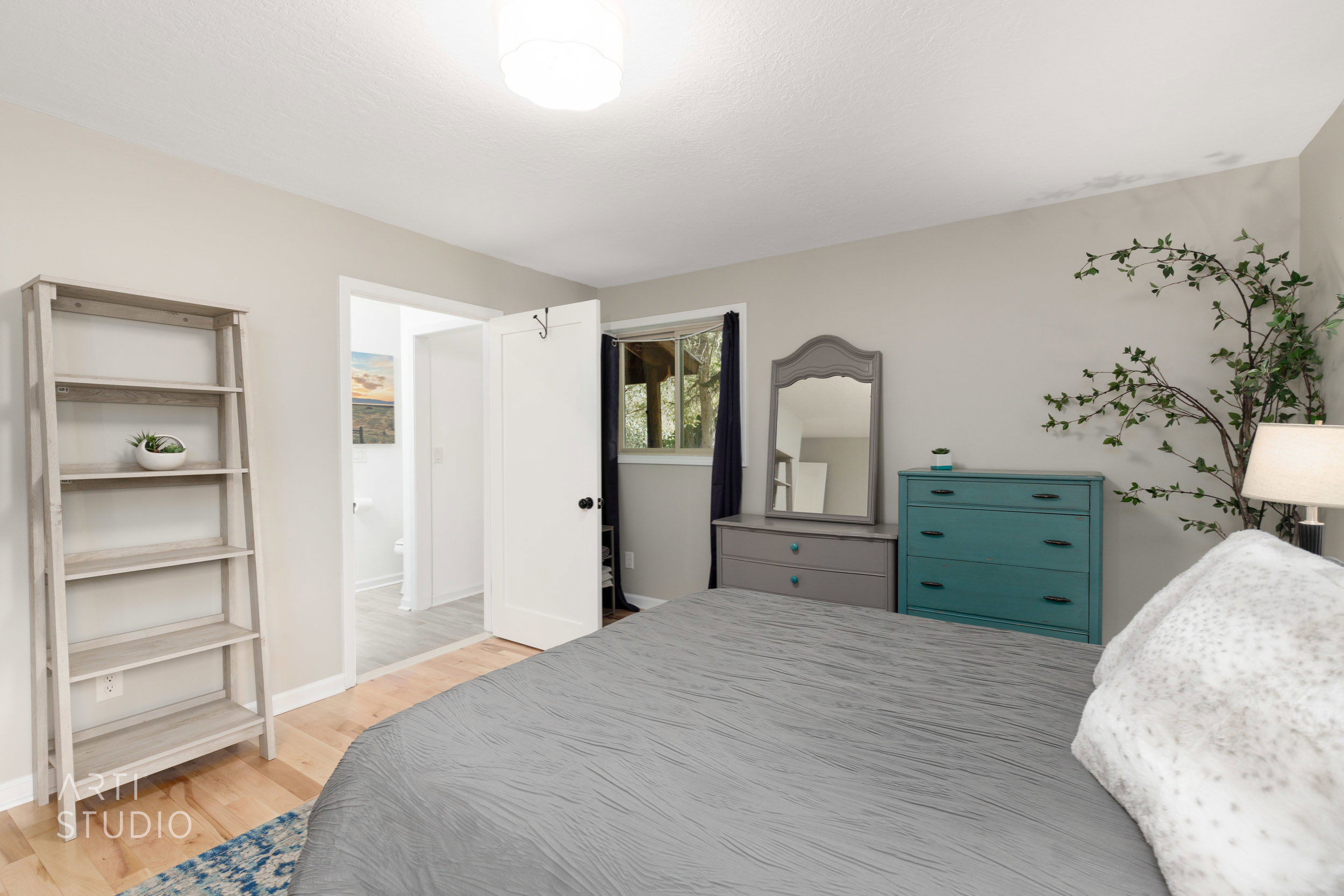 Hardwood-style flooring and light-toned walls define this space, featuring a window with dark drapes