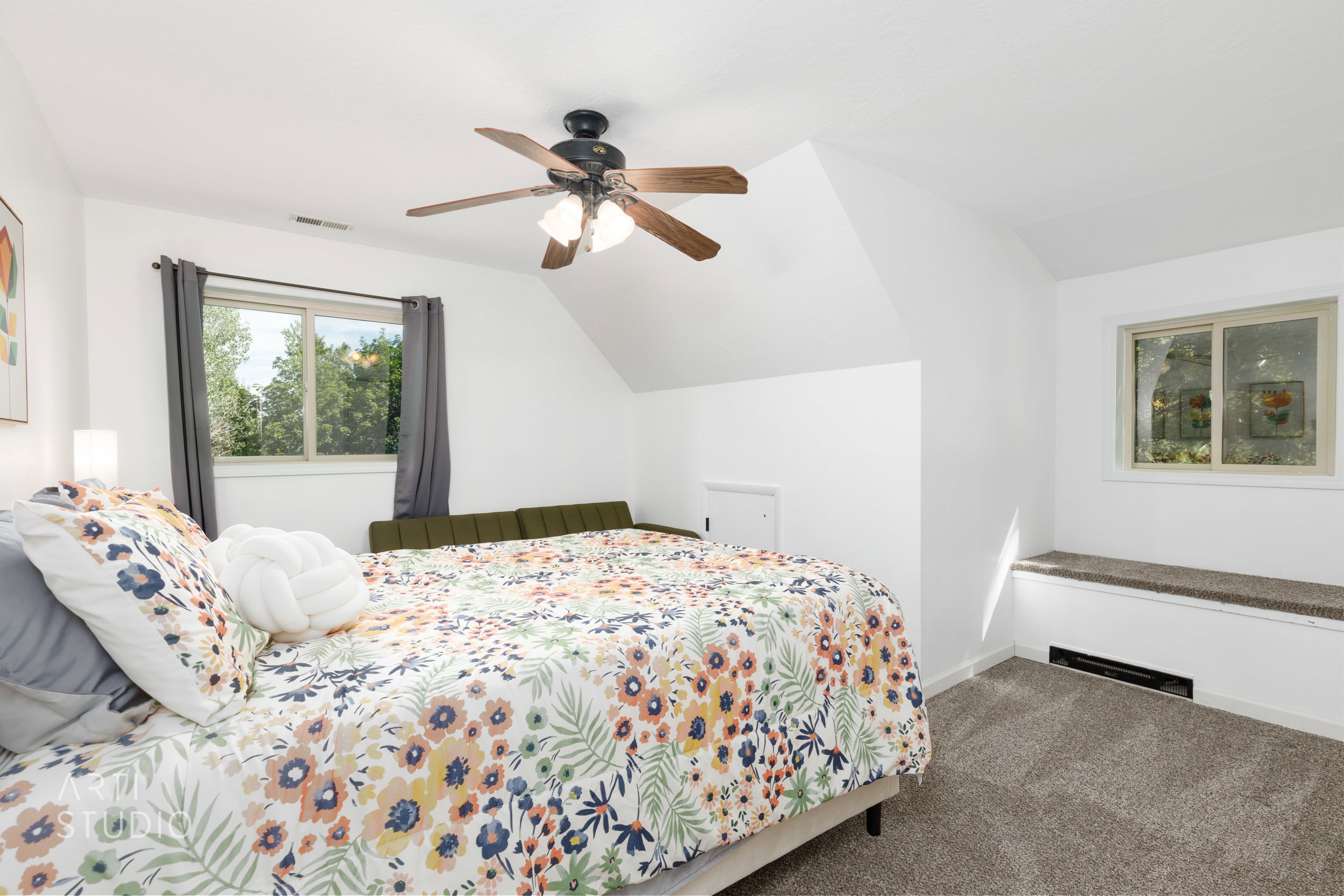 Carpeted room featuring a ceiling fan, two windows, and a built-in window bench