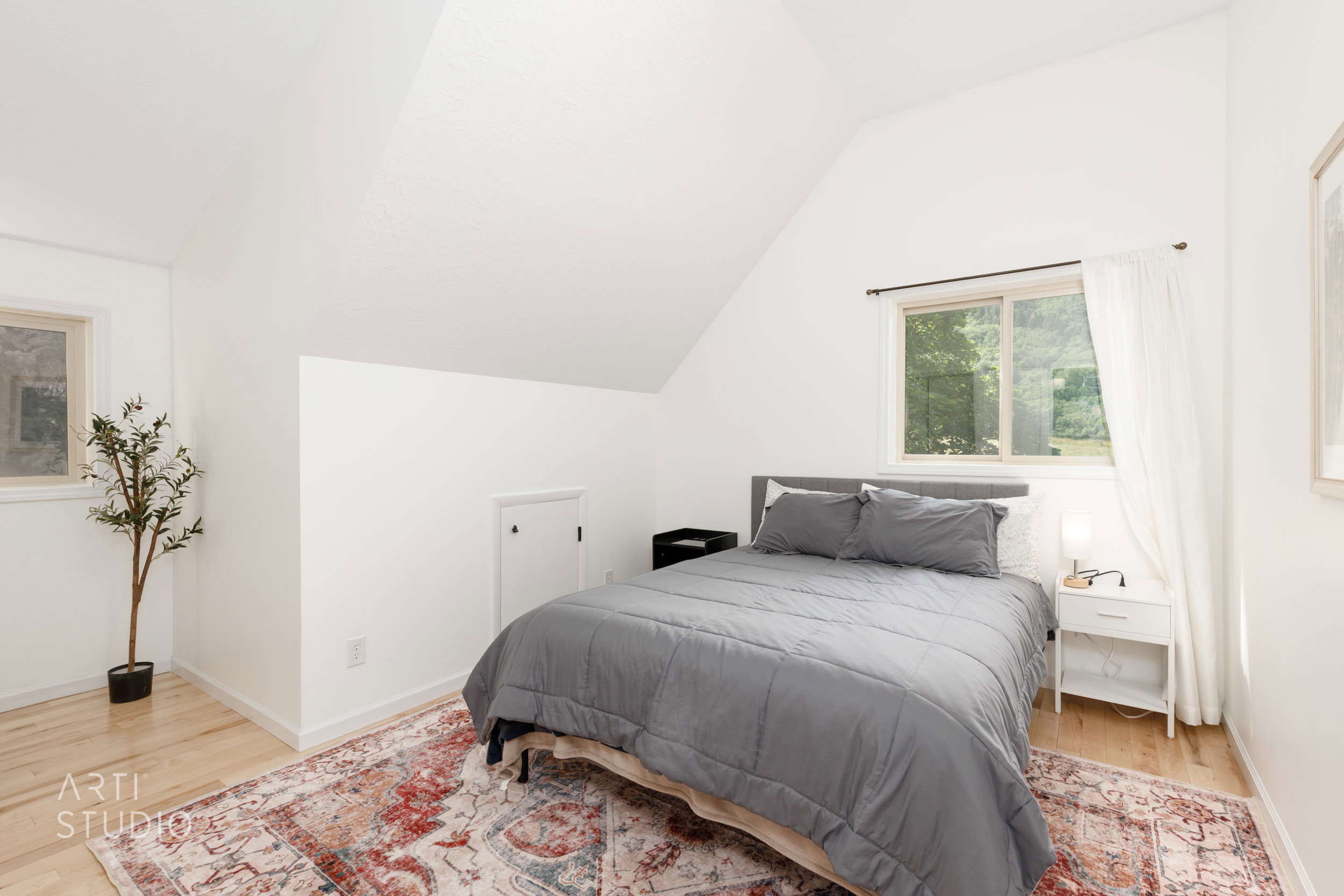Bedroom featuring light wood-finish flooring, white painted walls, and an angled ceiling