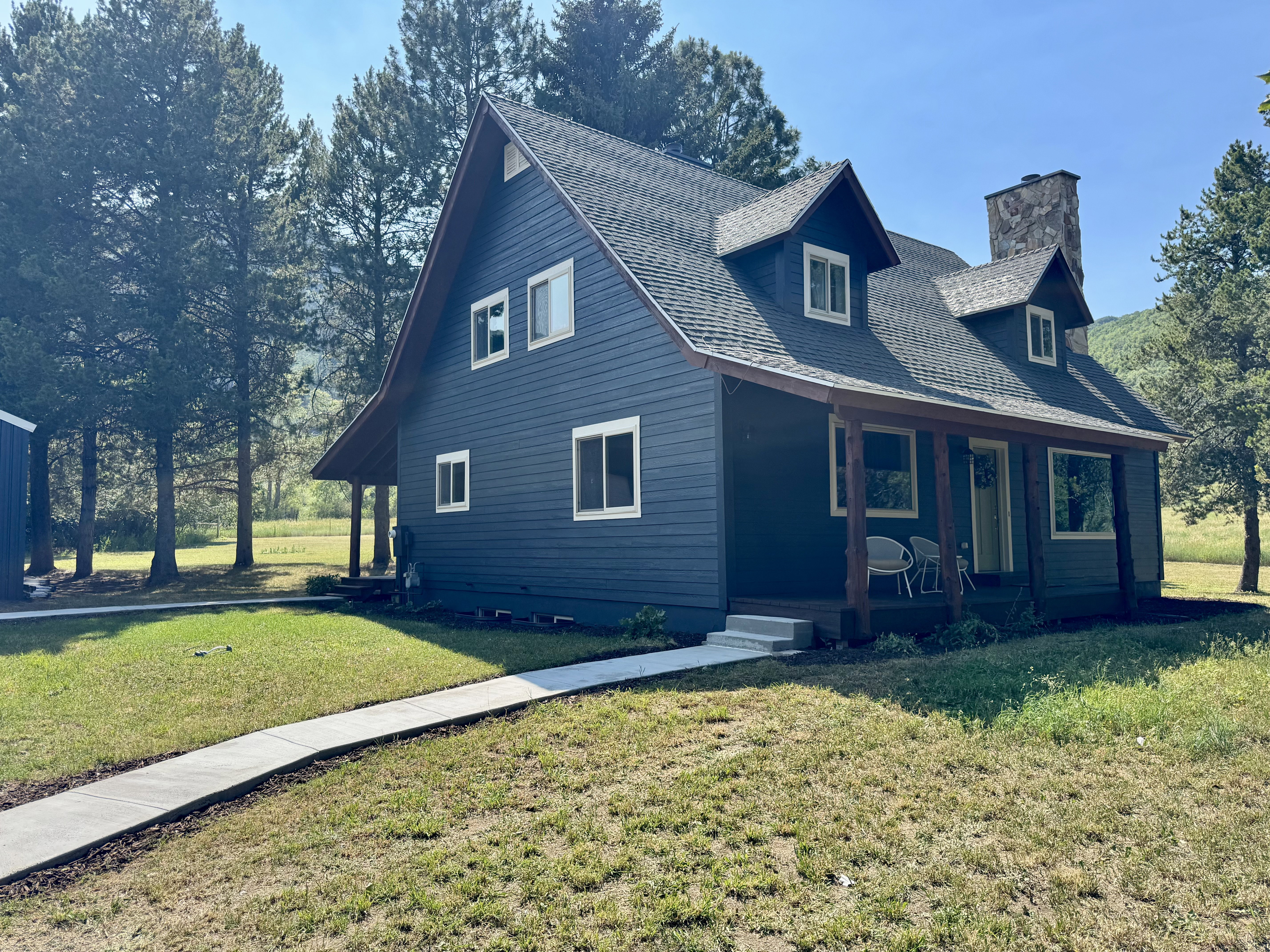 Dark blue siding exterior with a covered porch featuring wood support beams
