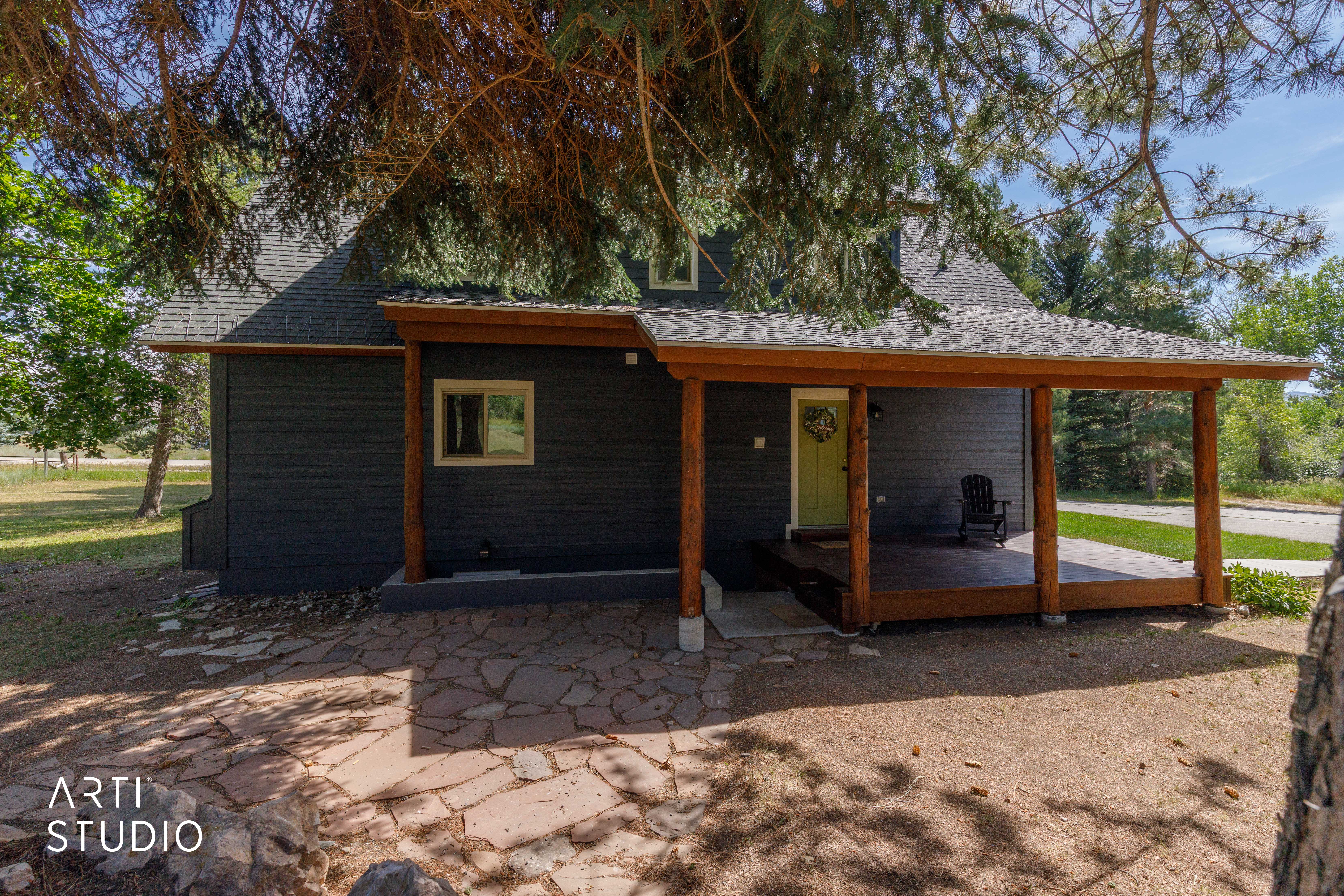 Charcoal siding exterior featuring a grey shingle roof and a spacious covered porch with natural wood posts and exposed beams