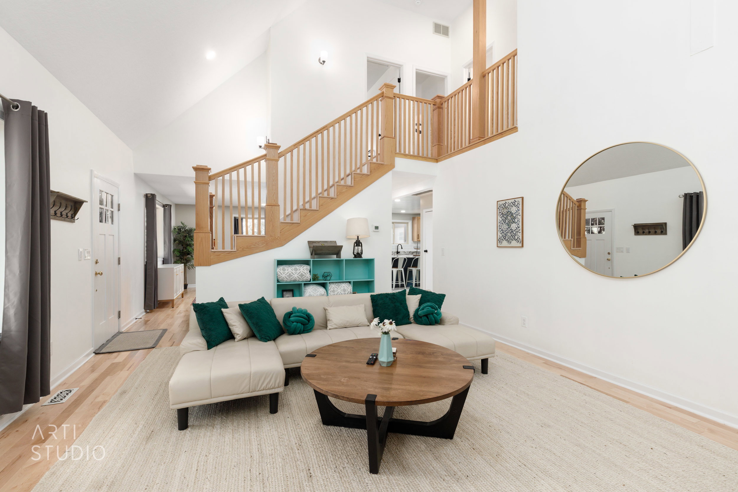 Vaulted ceilings enhance this living space featuring light wood-finish flooring and a wood staircase with balusters