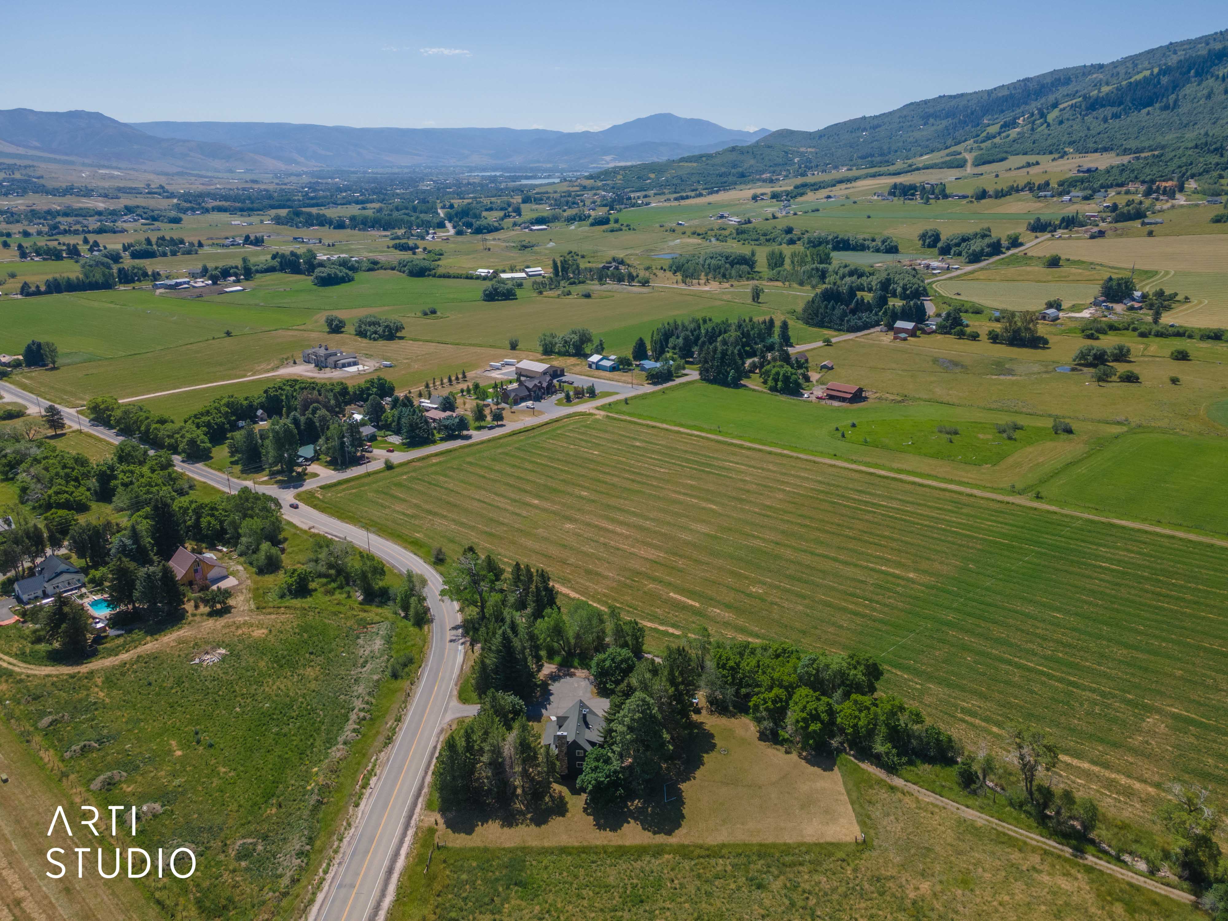 Expansive rural landscape featuring a single-family residence, mature trees, and agricultural fields