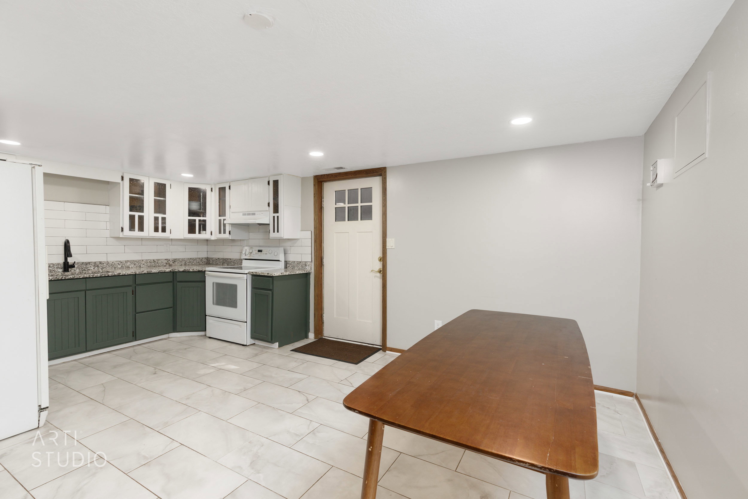Kitchen area featuring dual-tone cabinetry, white subway tile backsplash, and granite-style countertops