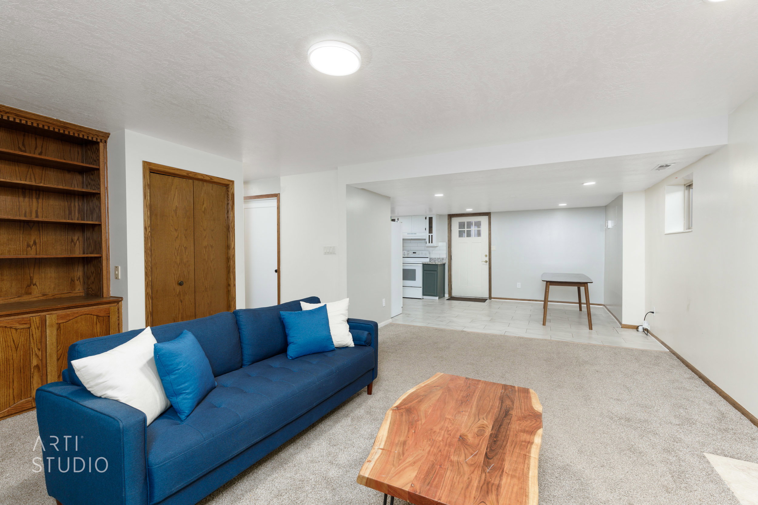 Spacious lower level featuring light gray carpeting, recessed ceiling lighting, and a built-in wood bookshelf