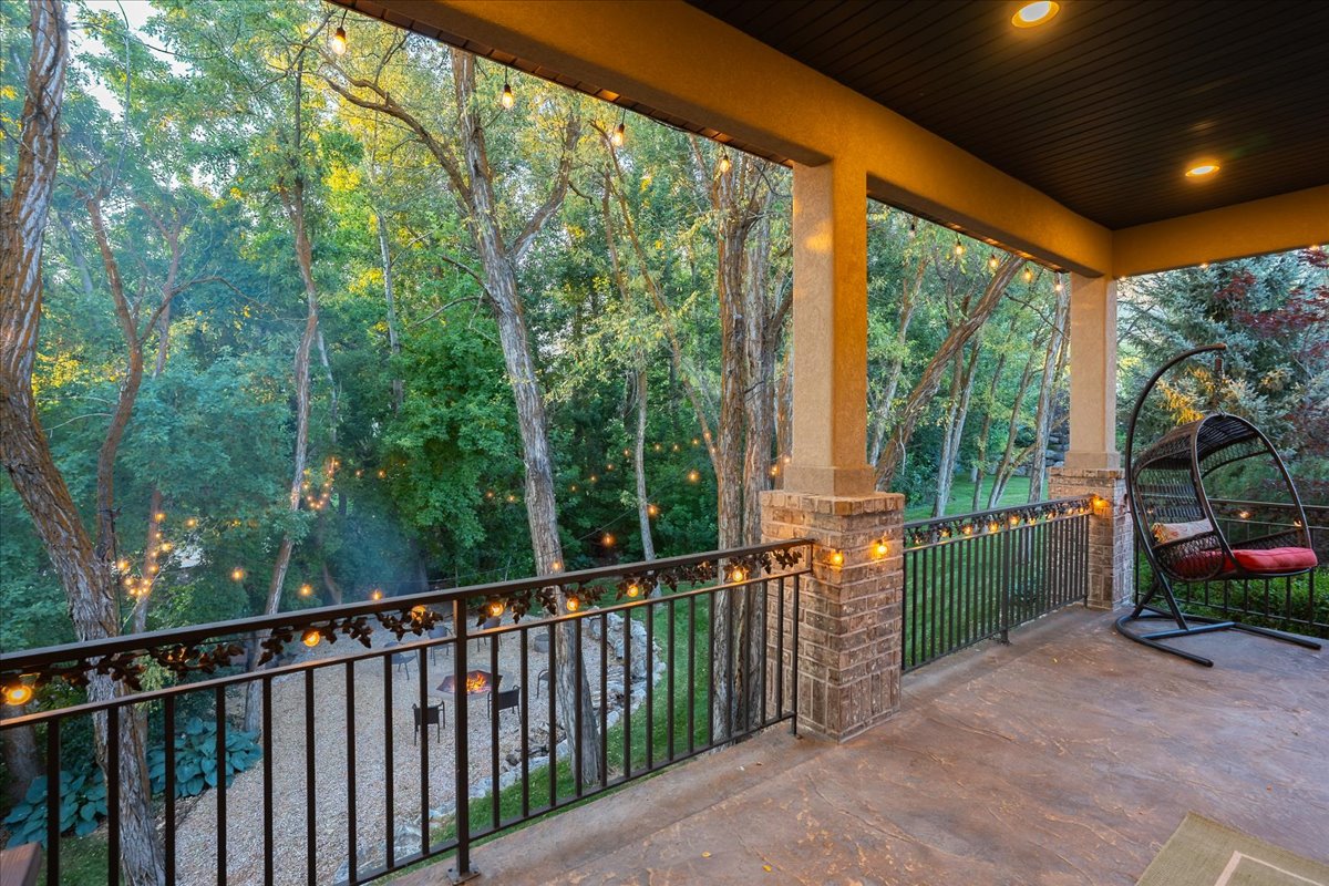 Covered outdoor patio featuring recessed lighting, string lights, and a decorative wrought iron railing with brick pillars
