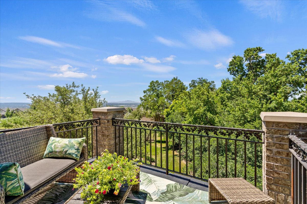 Elevated outdoor patio featuring brick masonry columns with stone caps, decorative wrought iron railing, and a clear sky overhead