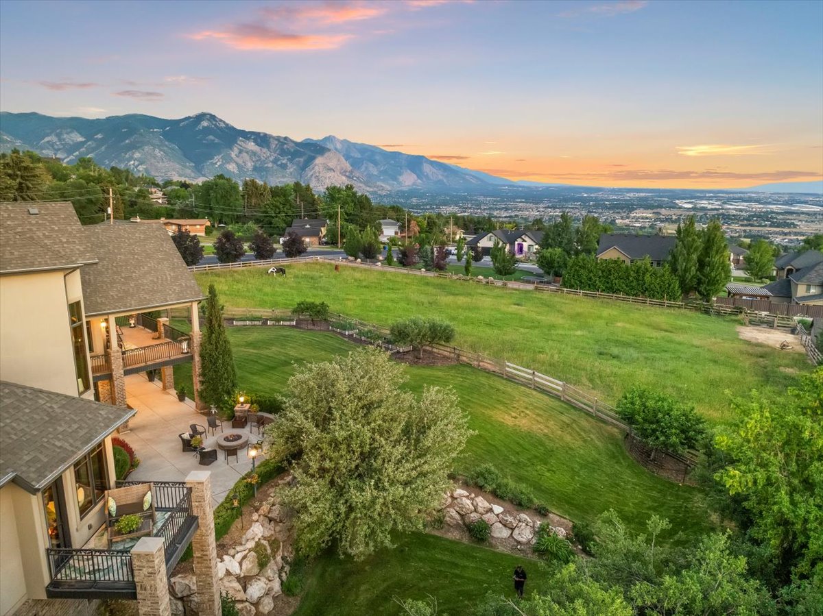 Expansive outdoor living area featuring multiple patios, terraced landscaping, and a substantial grassy expanse