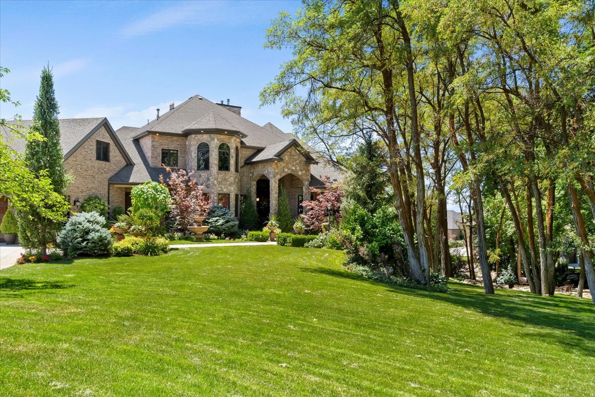 Stately brick and stone residence featuring a prominent turret, arched entryway, and multiple gables